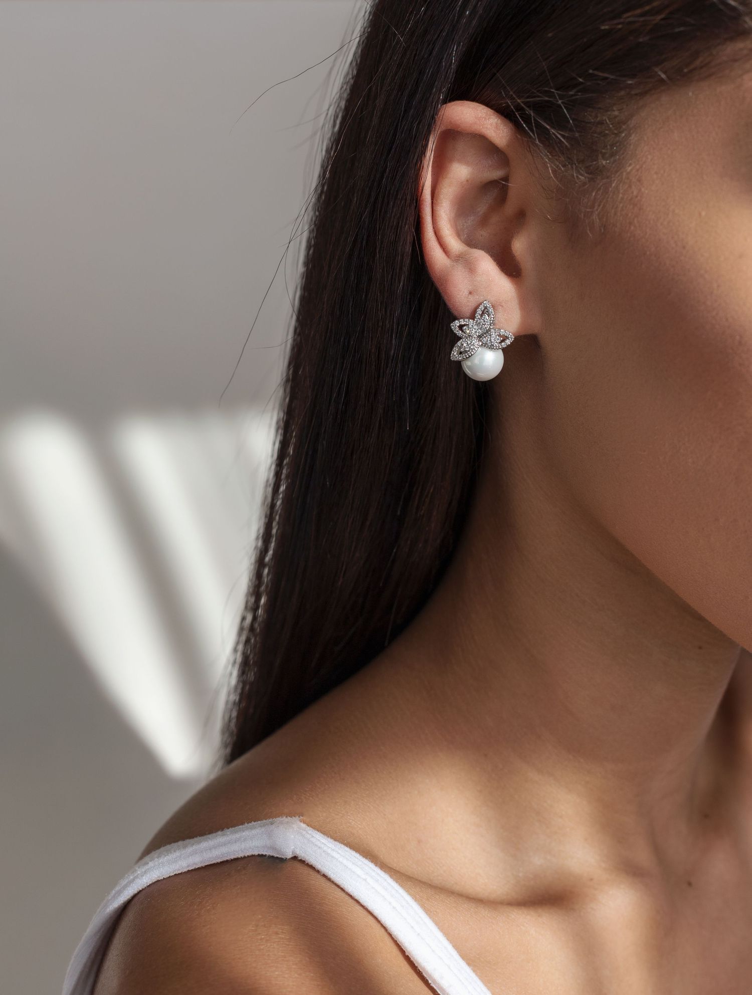 Pearl and crystal floral stud earring shown in natural window light.