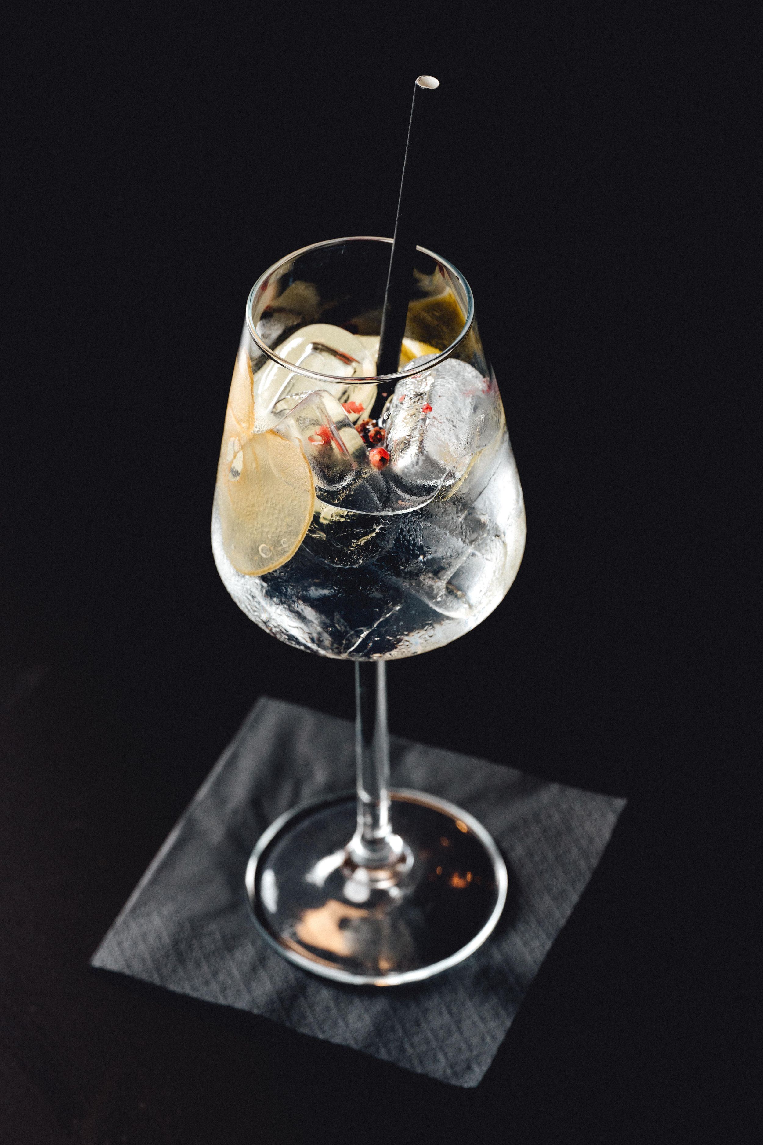 Crystal cocktail glass with clear liquid and garnish on black napkin.