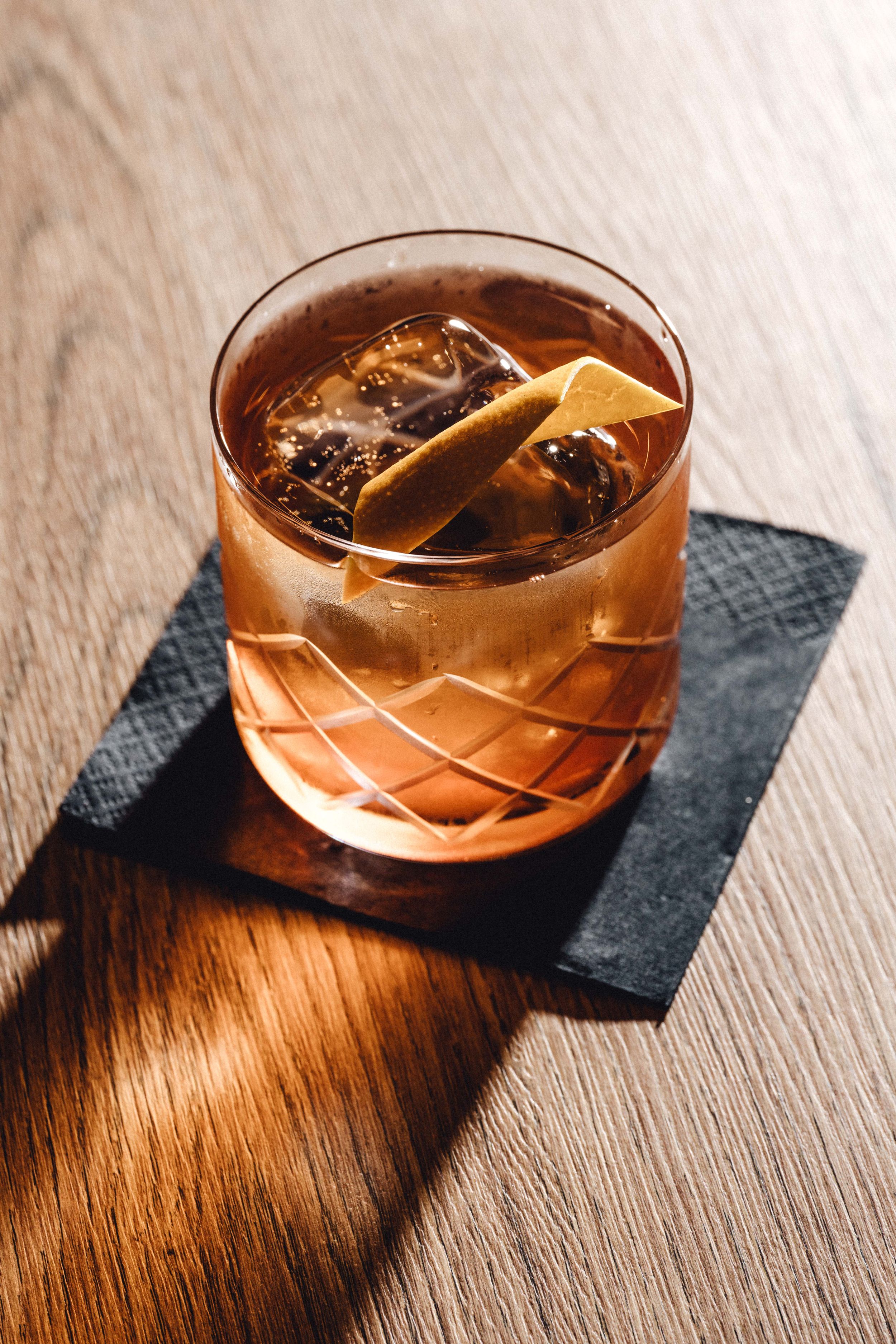 Copper cocktail in crystal glass on slate coaster with dramatic lighting.