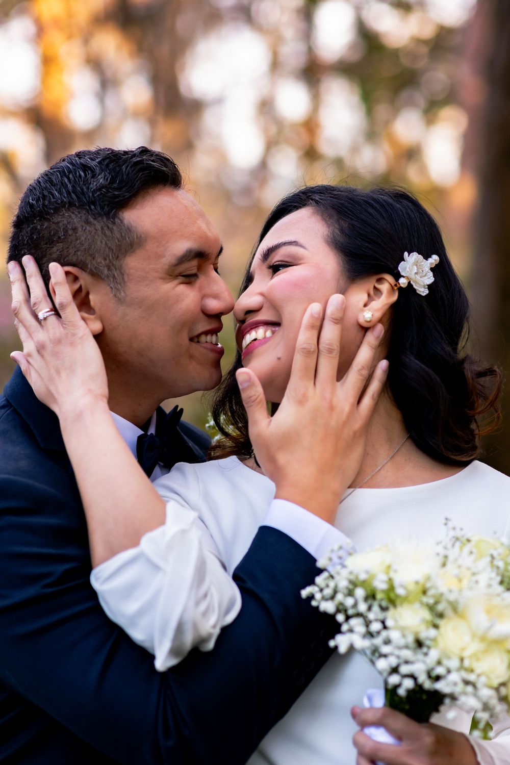 A joyful intimate moment between a couple holding a white flower bouquet.