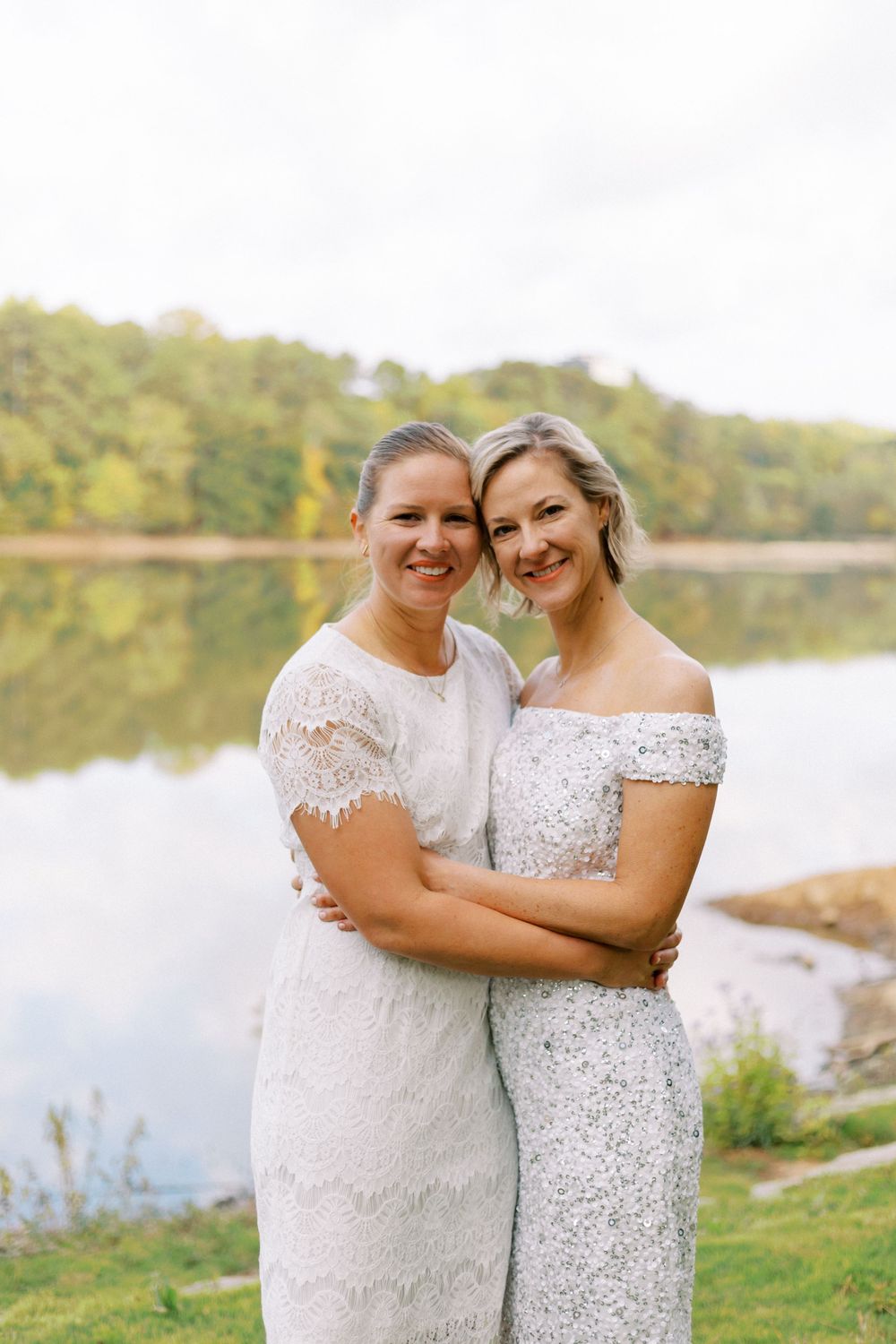 Two brides snuggle close on the edge of a lake Atlanta, GA elopement