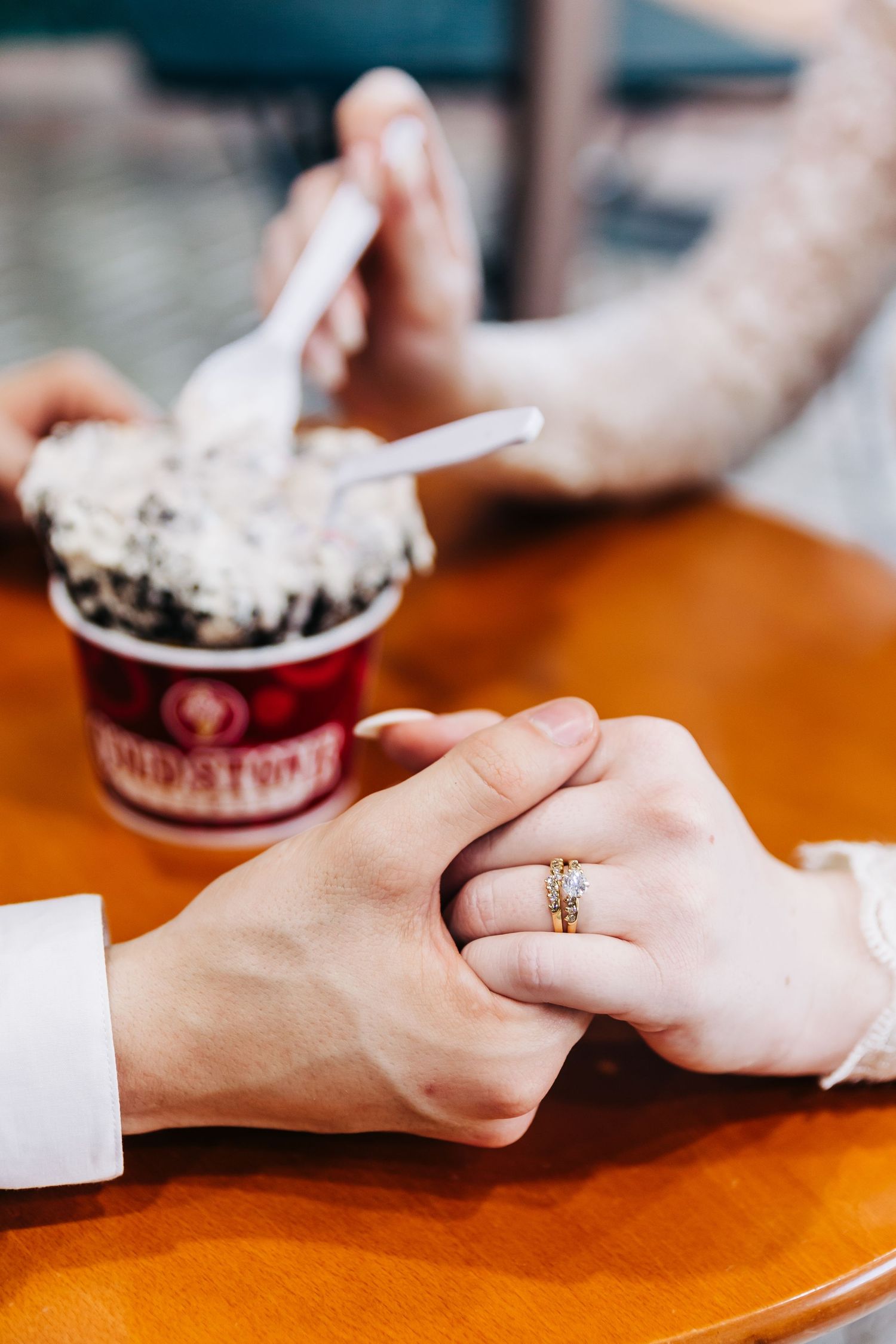 Close up of hands with engagement ring sharing ice cream dessert.