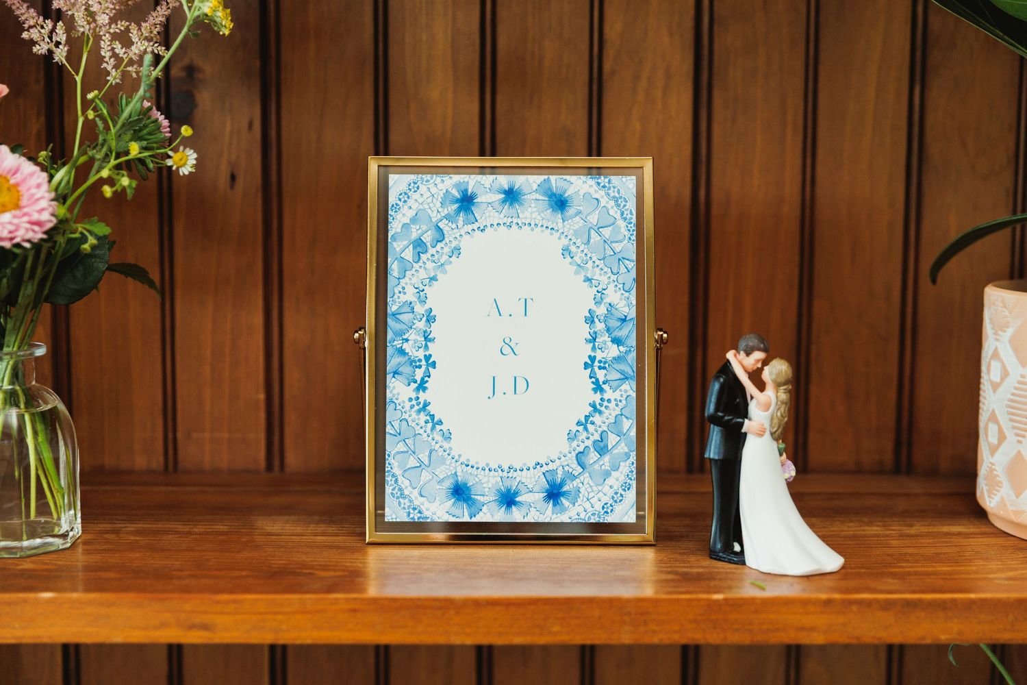 Rustic wooden shelf displaying decorative blue and white frames with floral accents.