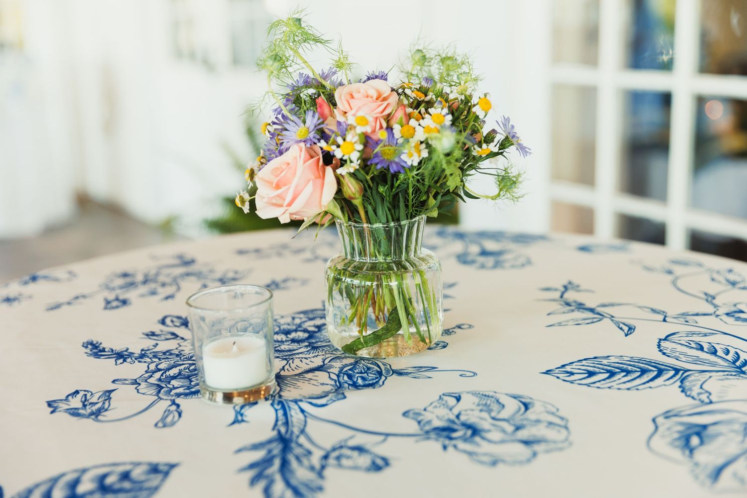 Blue and white patterned tablecloth with fresh floral centerpiece arrangement.