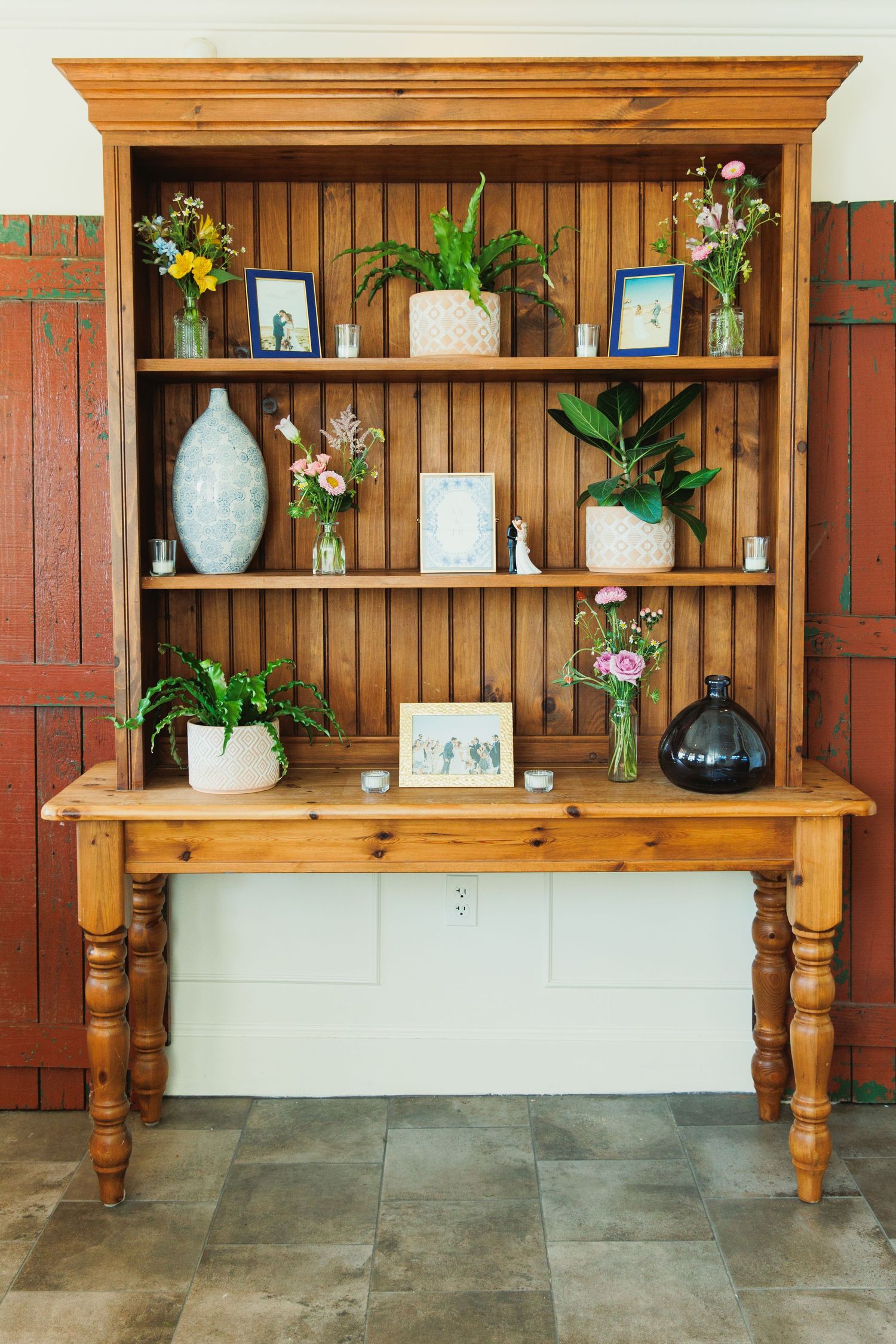 Wooden display shelf with ornate turned legs decorated with vases and floral arrangements.