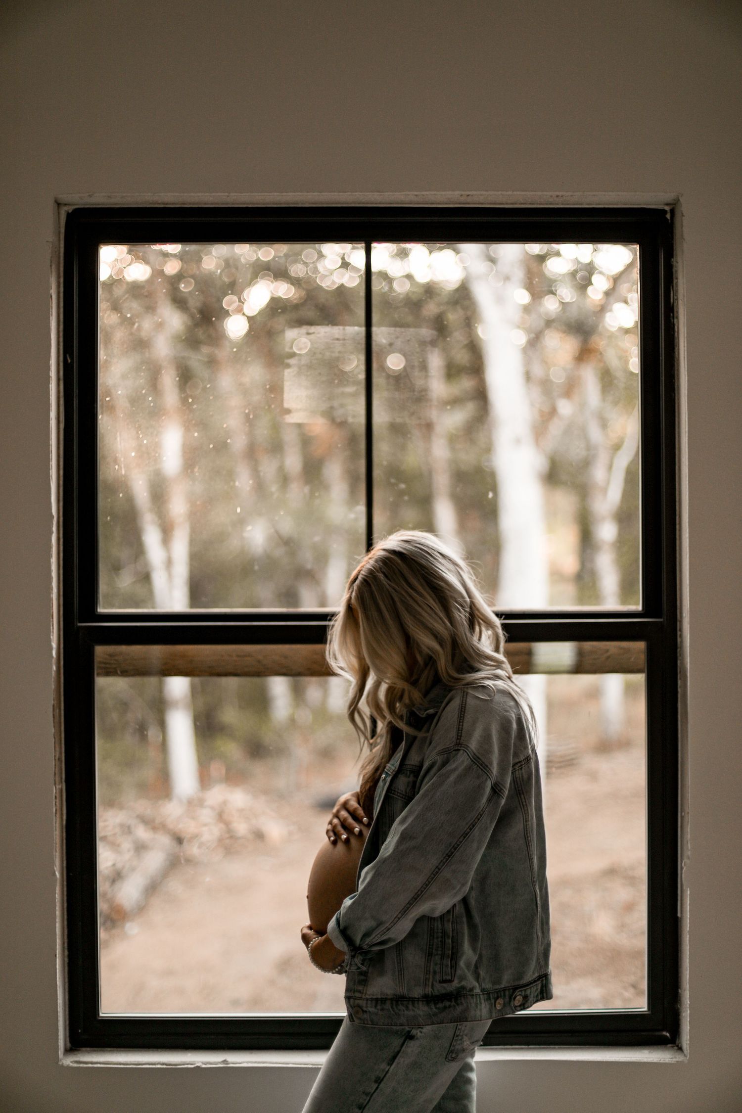 Silhouette by window showing expectant figure in denim jacket during golden hour.