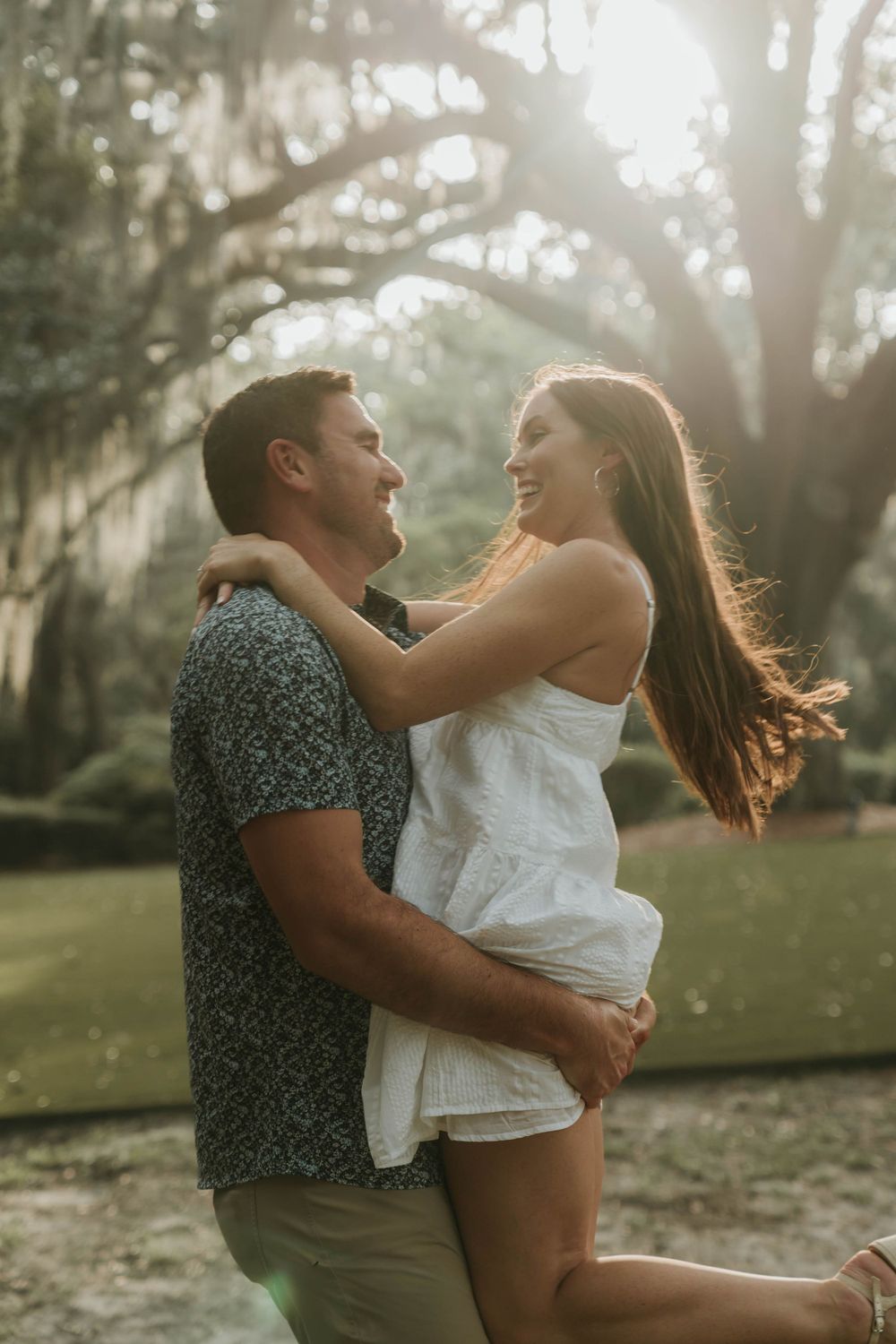Couple sharing a joyful moment together in a dreamy outdoor setting with glowing sunlight.