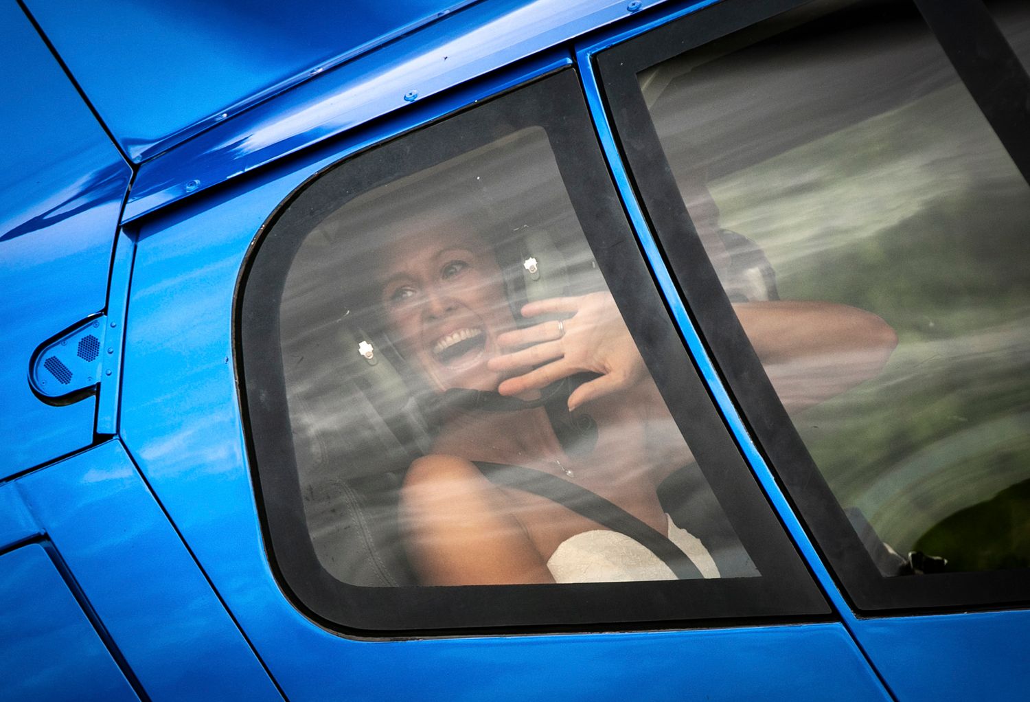 Close-up detail of a bright blue car's side panels and windows reflecting sunlight.