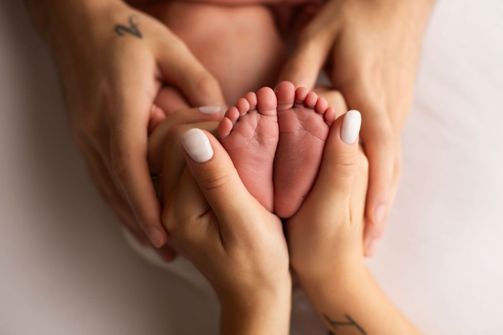 Image of newborn baby boy's feet held by mom and dad.