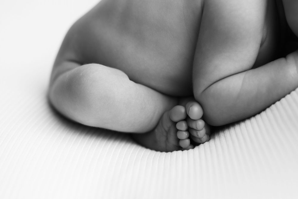Newborn baby boy in black and white image.  Close up of all ten tiny toes.