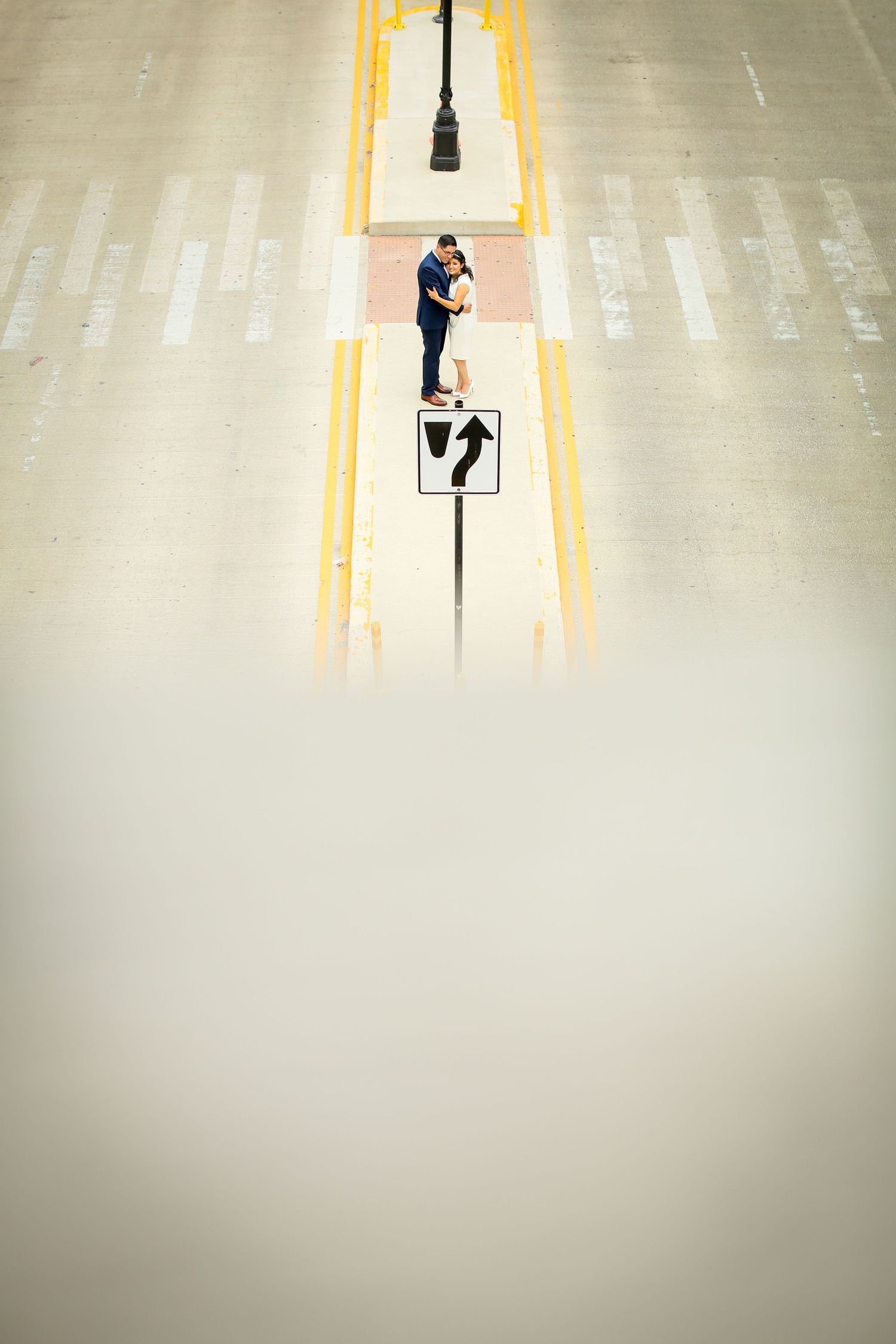 Aerial view of a crosswalk with yellow lines and pedestrian crossing sign.