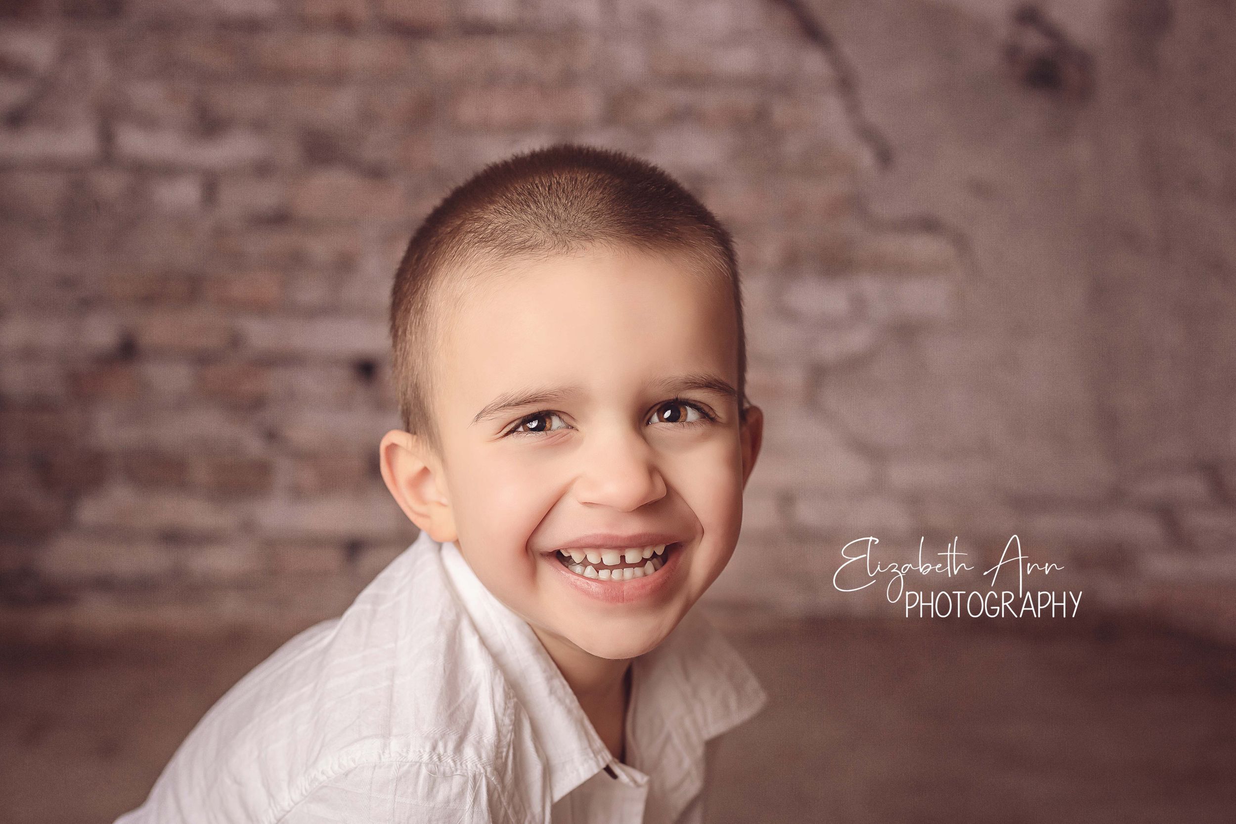Studio portrait with brick backdrop, closeup of a smiling child, by Elizabeth Ann Photography, Wisconsin, USA