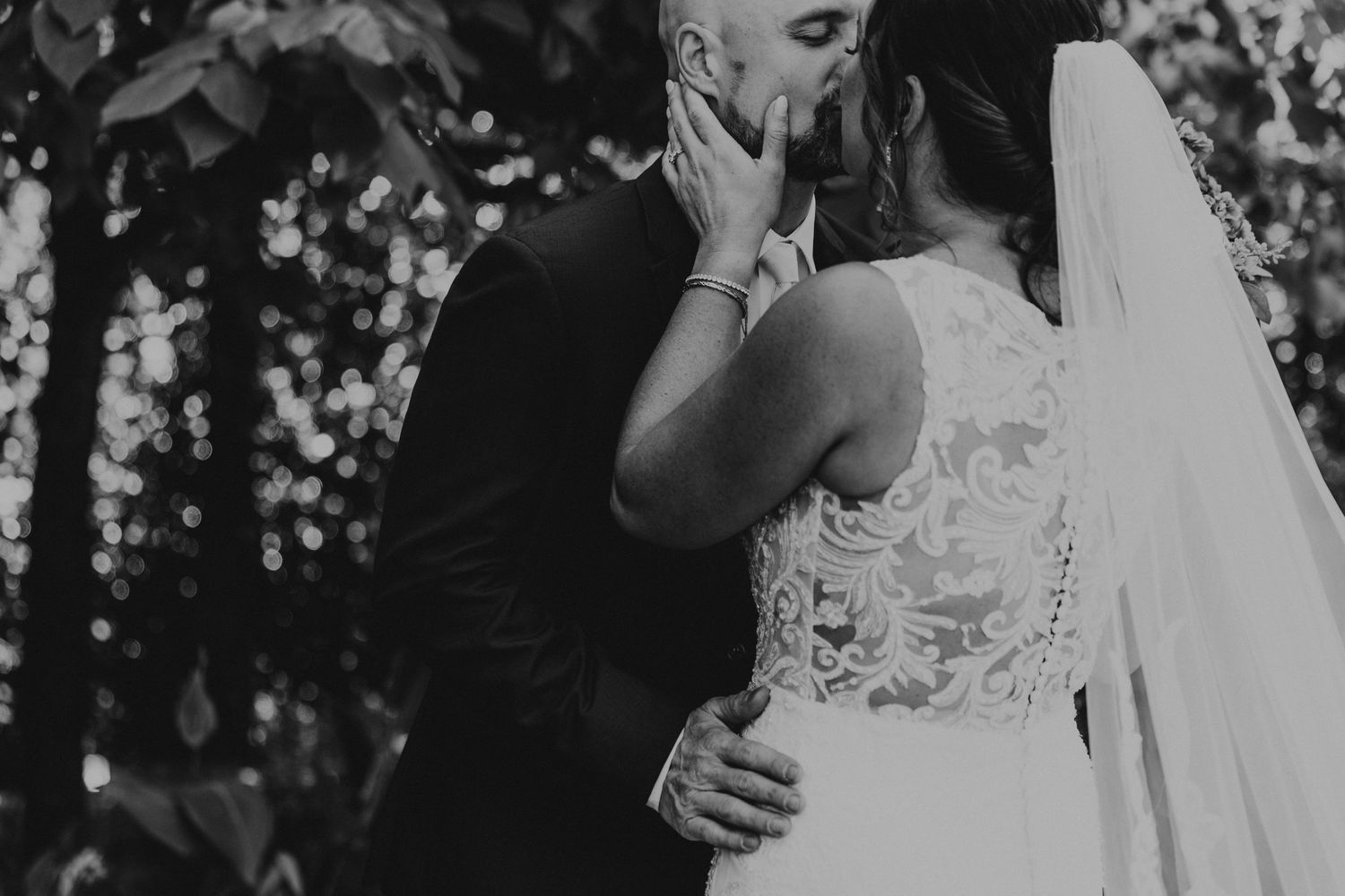 Intimate black and white wedding moment with bride in lace dress.