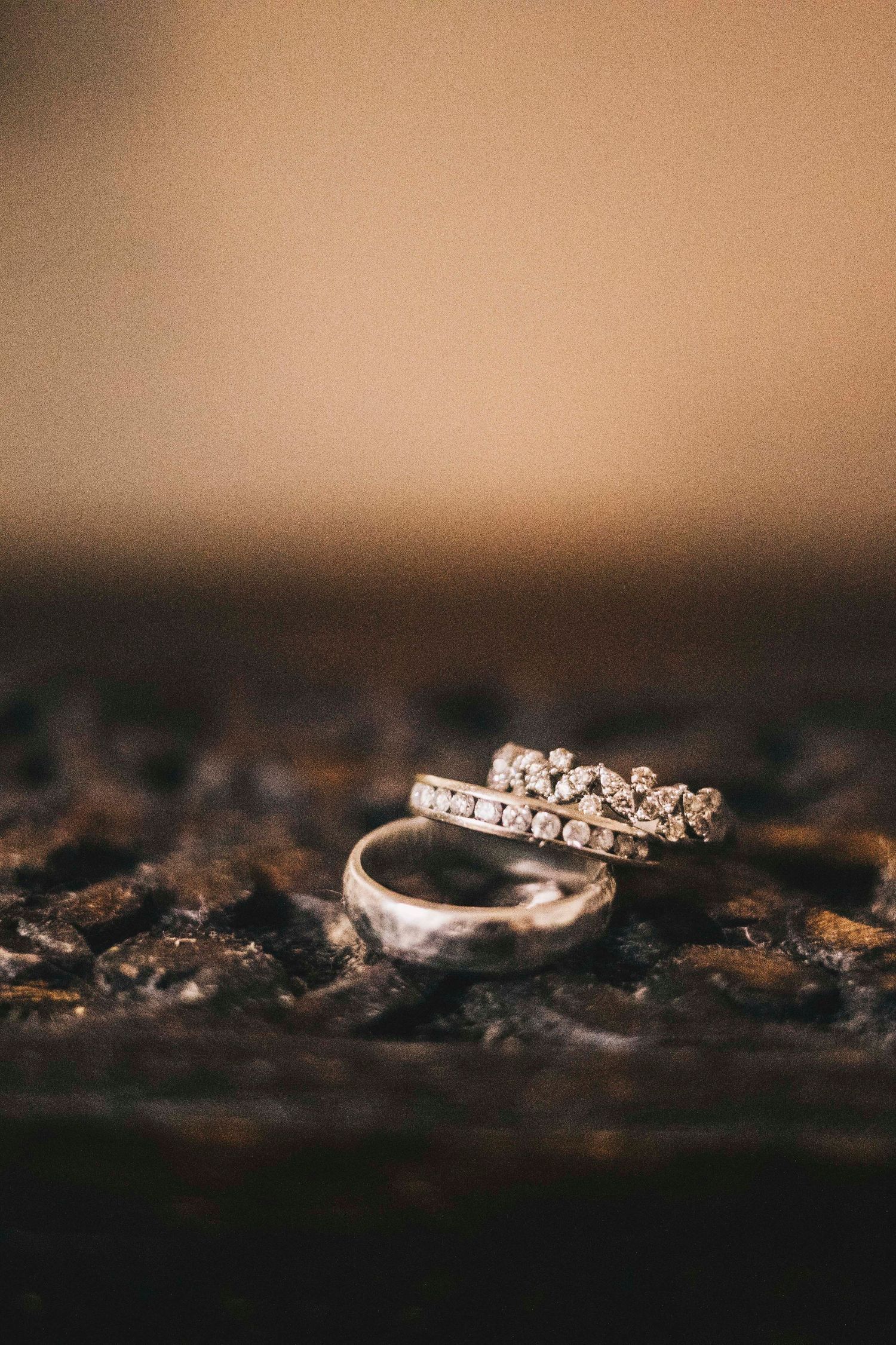 Diamond wedding band and plain gold ring displayed on dark surface.