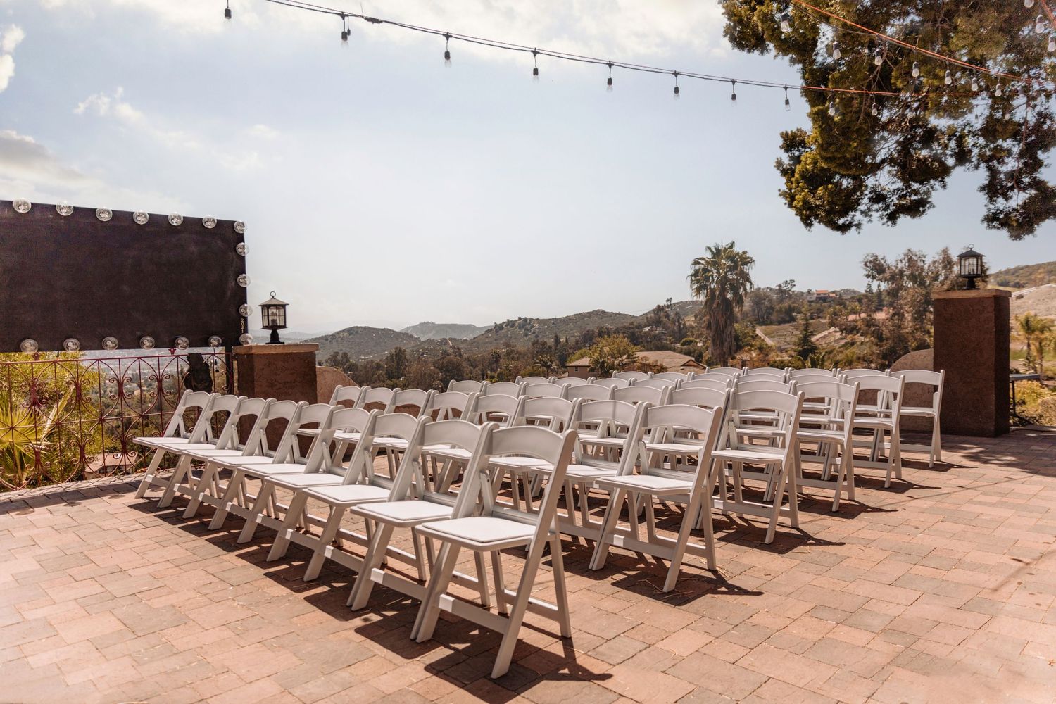 White folding chairs set up for an outdoor wedding ceremony with mountain views.