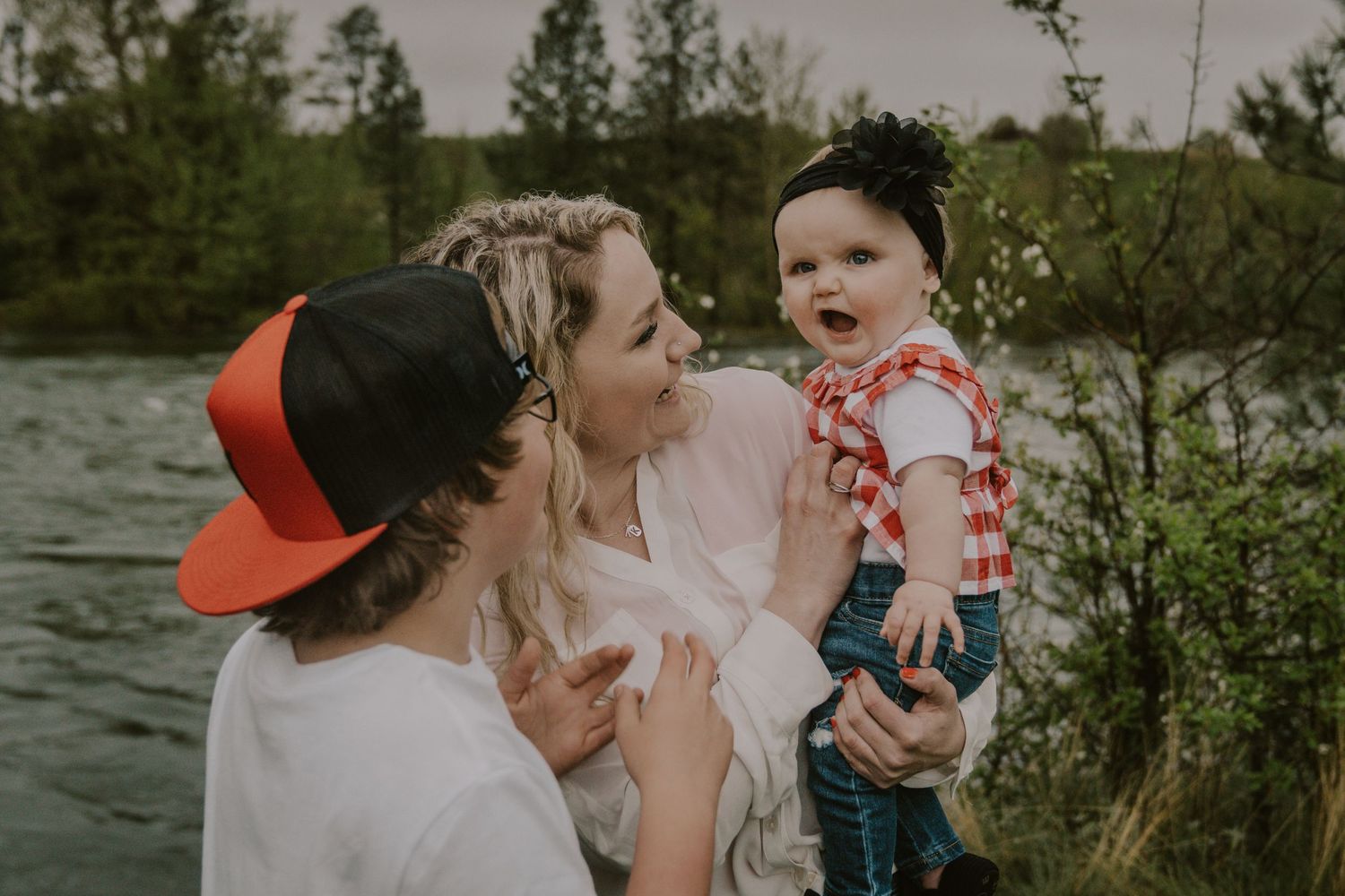 Family moment by the river with parent and child sharing a playful interaction.