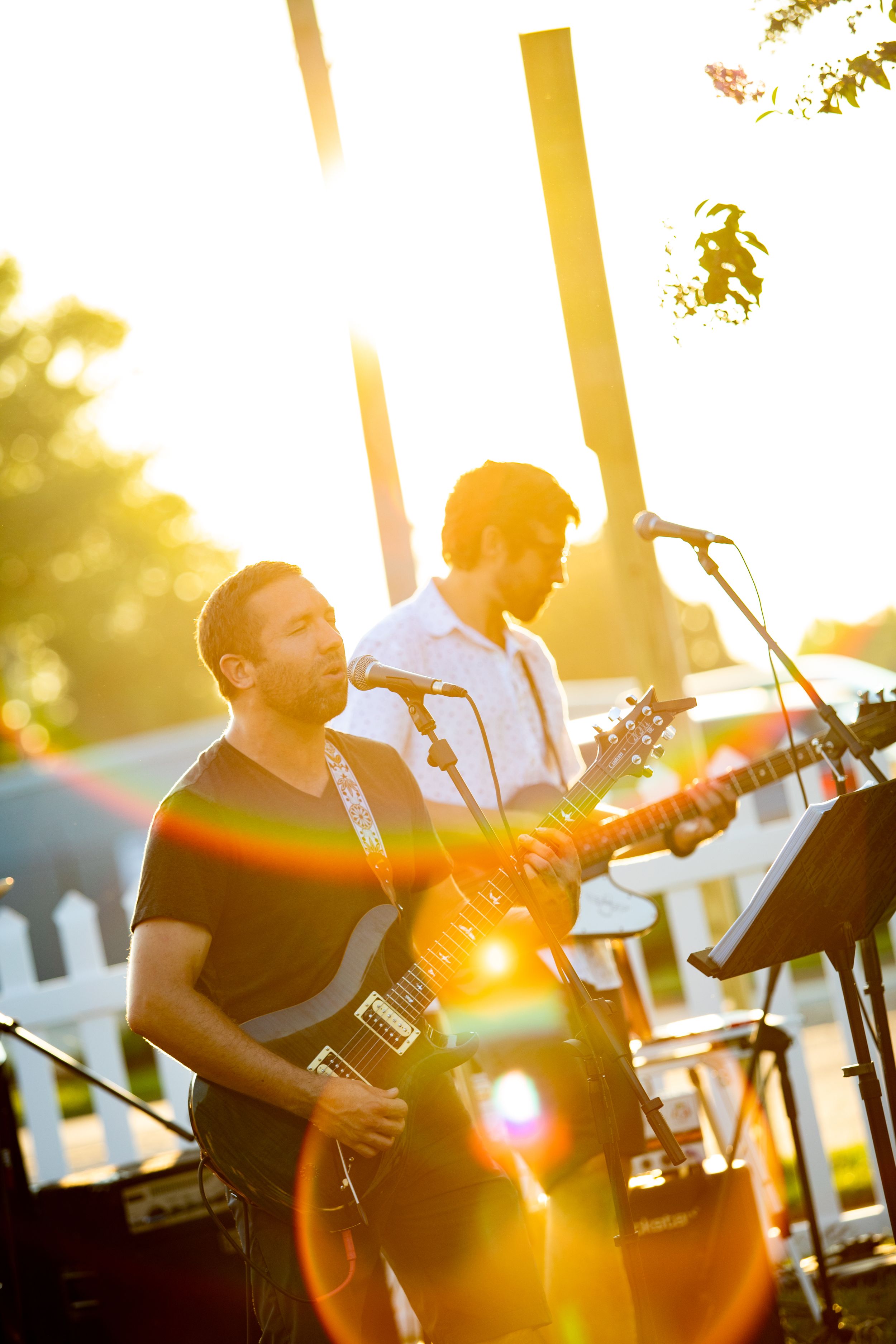 Band members playing instruments in golden sunset light during outdoor performance.