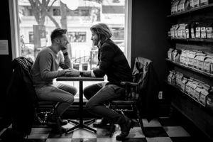 A couple shares an intimate conversation at a retro diner booth in black and white.