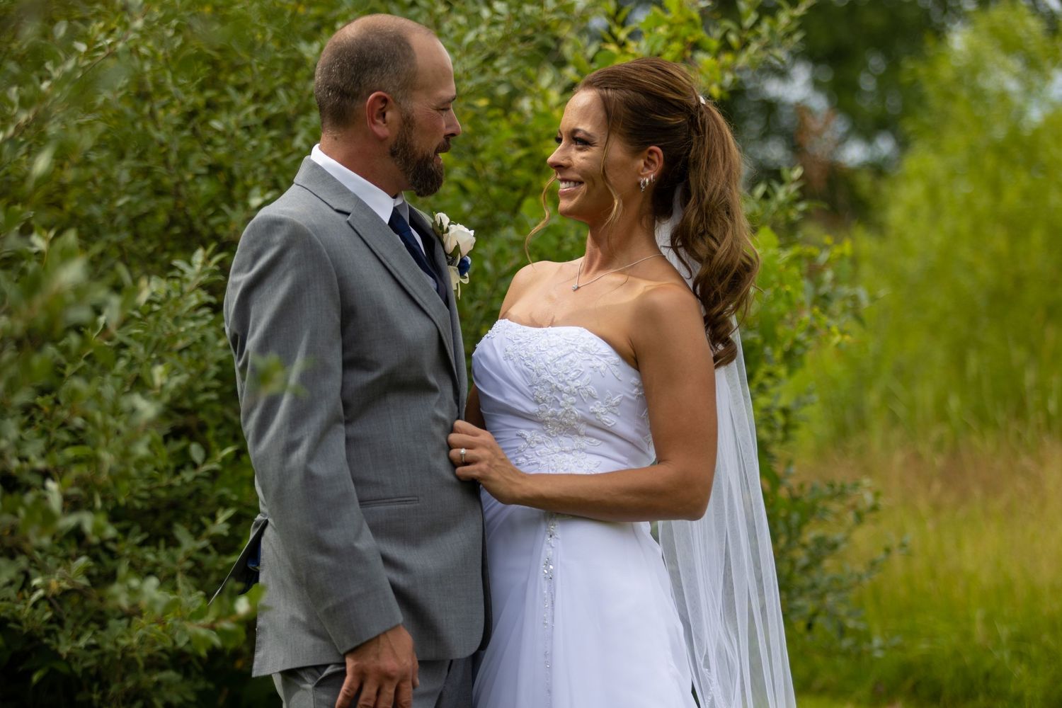 Newlyweds share romantic moments in a lush green garden setting.