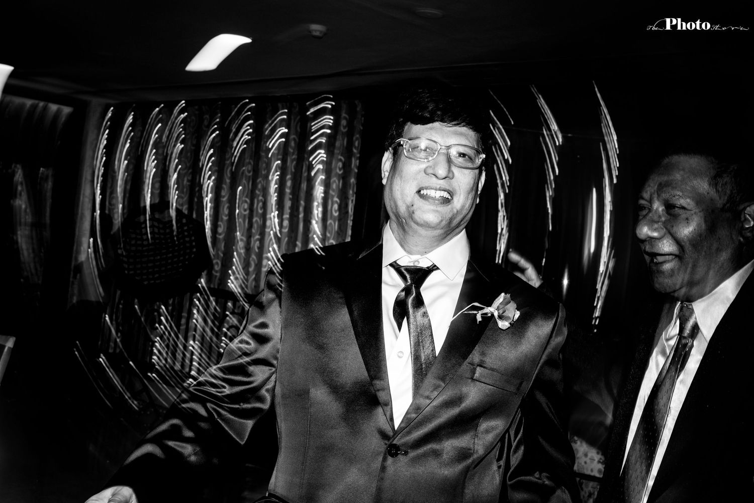 A black and white candid shot of joyful laughter during wedding festivities.