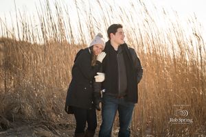 Couple sharing a romantic moment among tall reeds during golden hour.