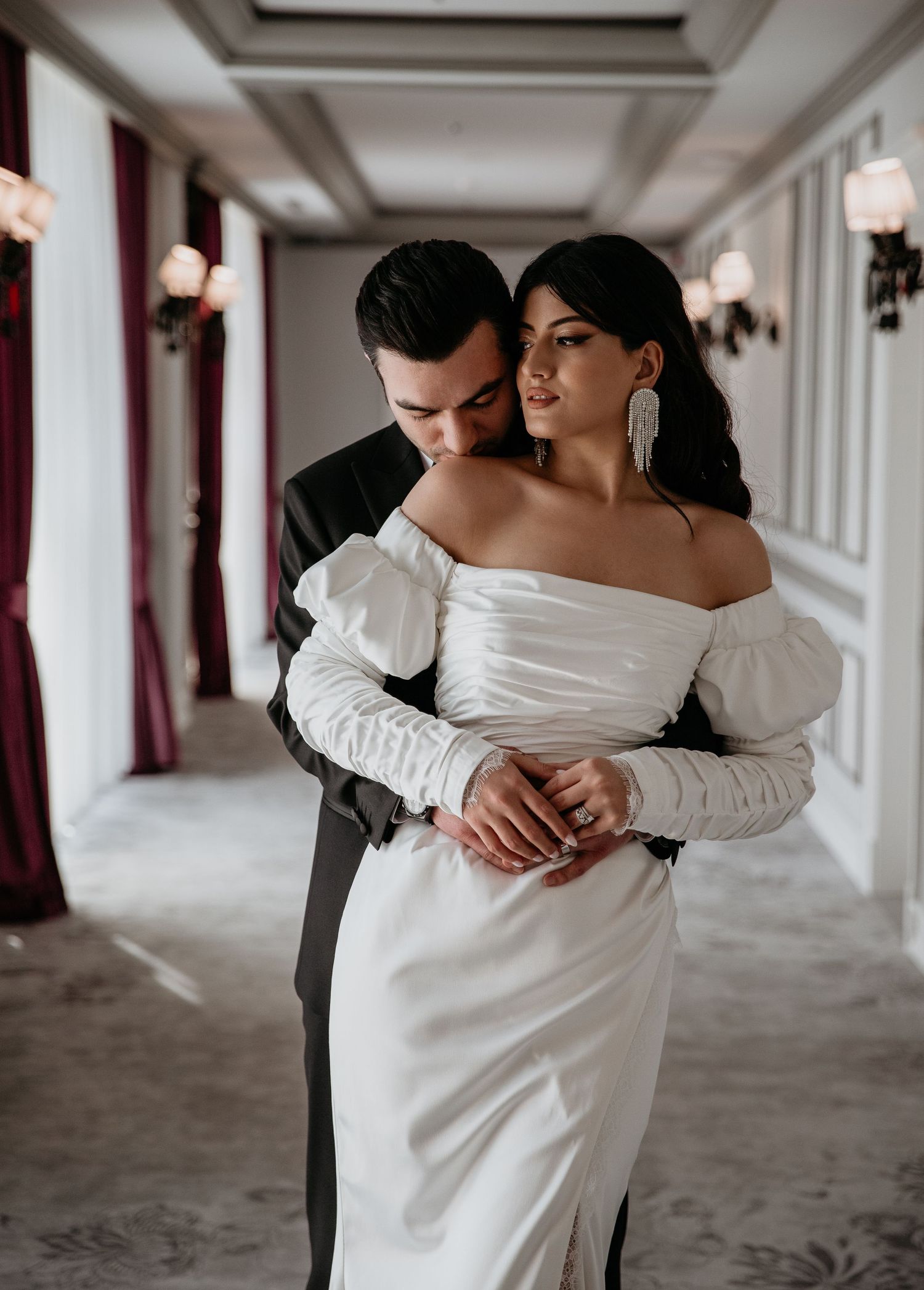 Romantic bridal portrait in an elegant hallway with dramatic lighting and off-shoulder wedding dress.