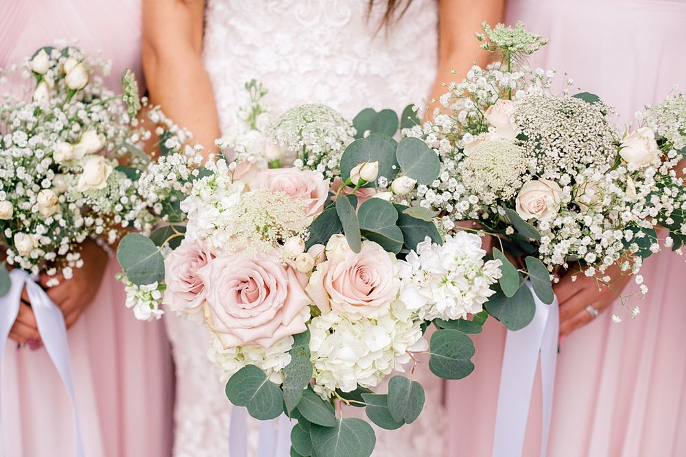 Delicate wedding bouquet featuring pink roses, white flowers, and eucalyptus greenery.