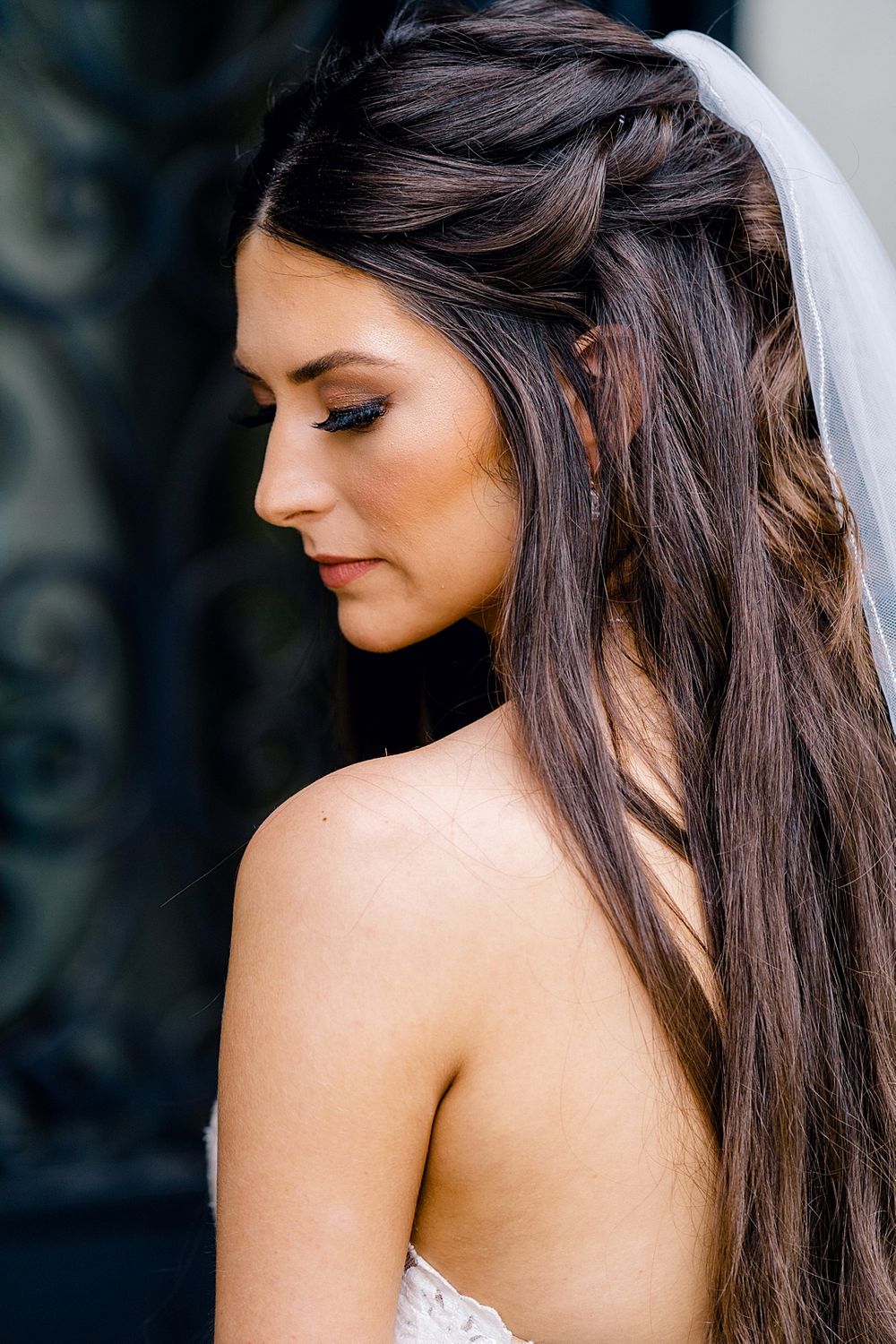 Side profile showcasing elegant bridal hair and makeup with long flowing dark hair.