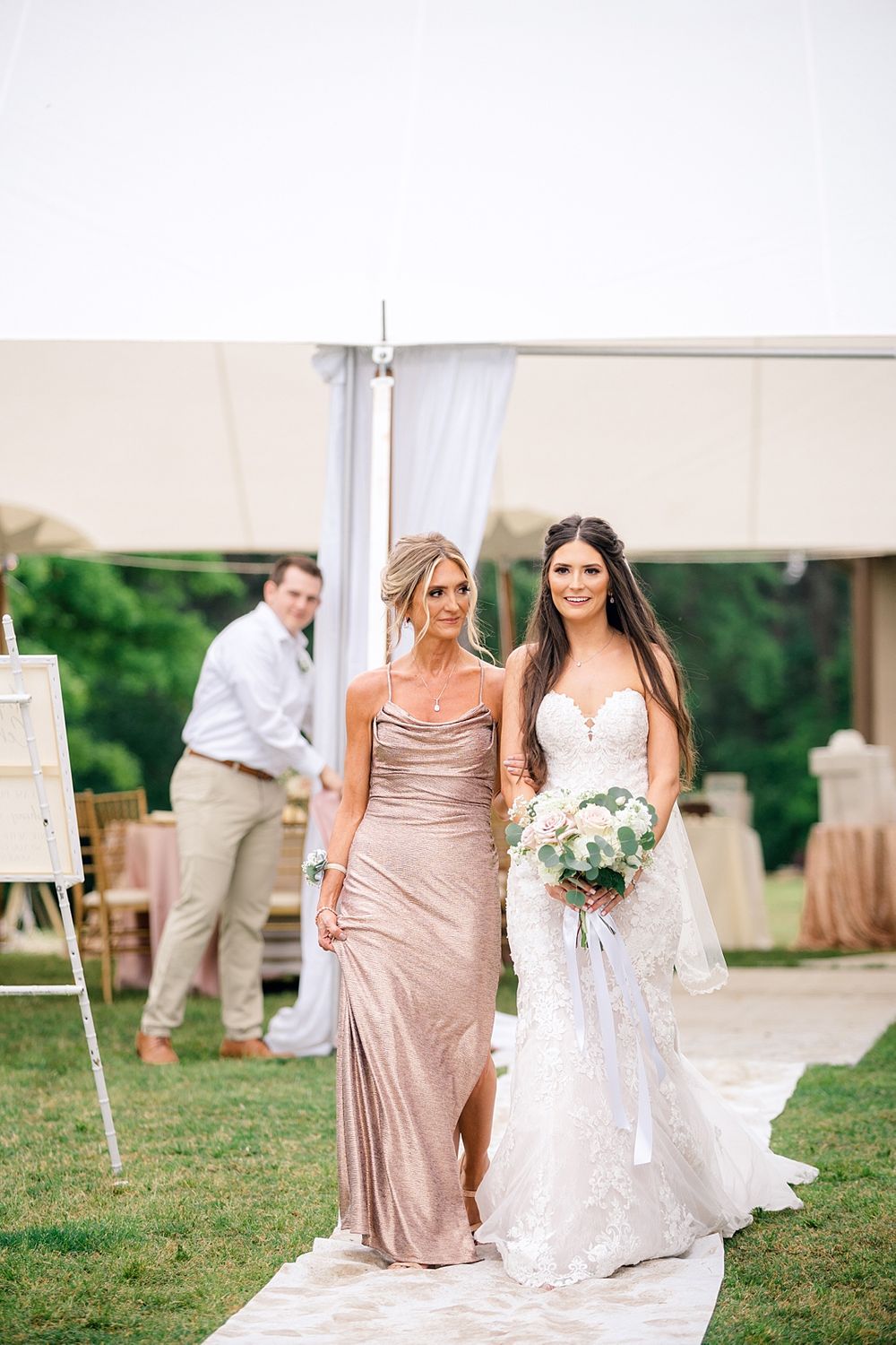 Elegant wedding party members posing on a white walkway outdoors.