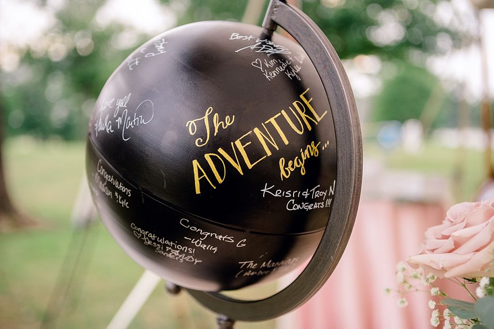 Decorative black globe with gold lettering reading 'The Adventure' as wedding decor.