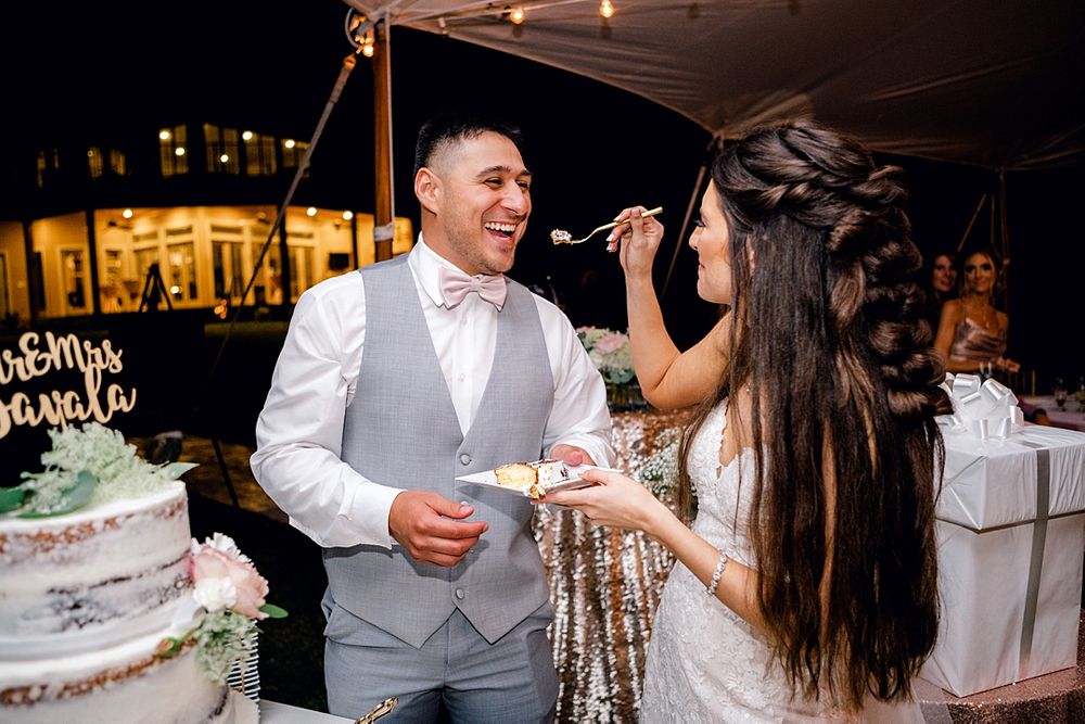 Wedding cake cutting ceremony with playful cake feeding moment under twinkling lights.