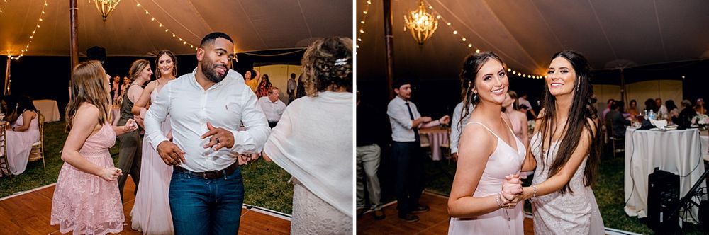 Guests dance and celebrate during a lively wedding reception in a tent with string lights overhead.