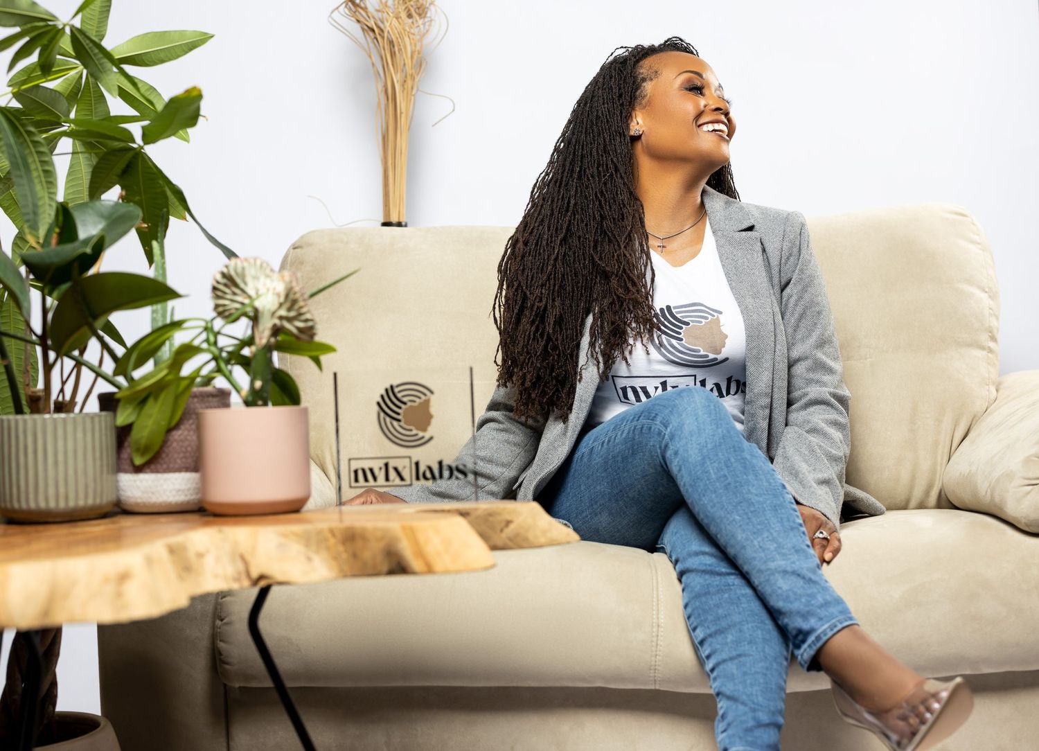 Woman relaxing on beige couch with houseplants and modern decor in background.