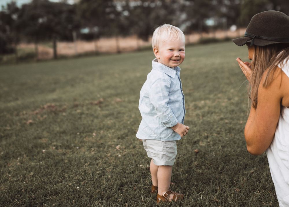 Playful interaction between two people in a grassy field during golden hour.