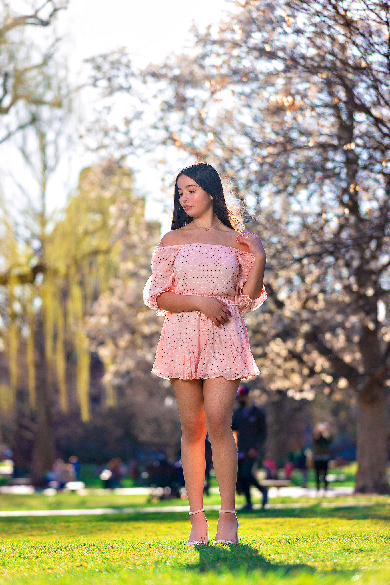 Spring garden portrait in pink off-shoulder dress surrounded by blossoming trees.