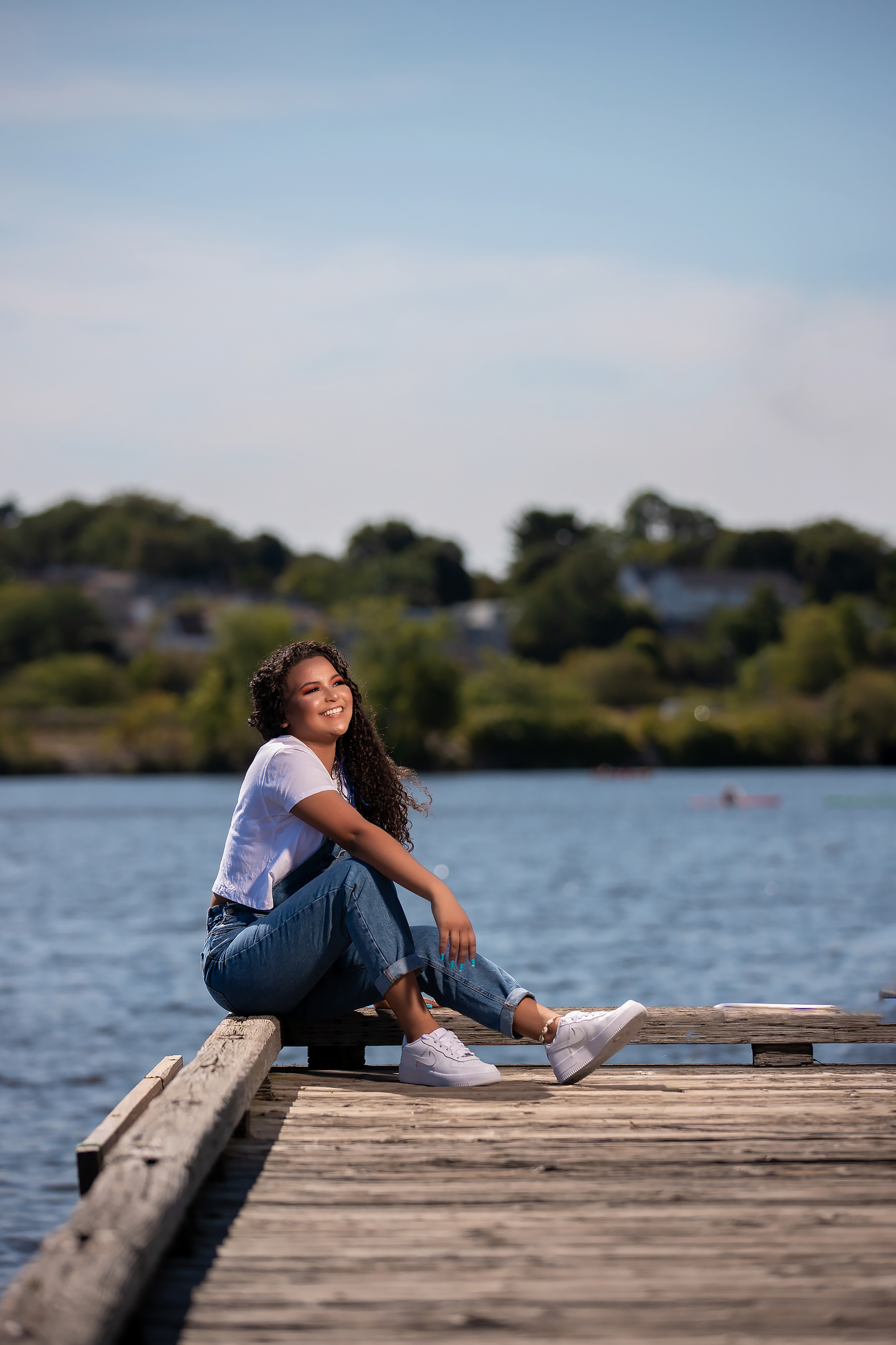 Casual waterfront portrait on wooden dock wearing white t-shirt and jeans.