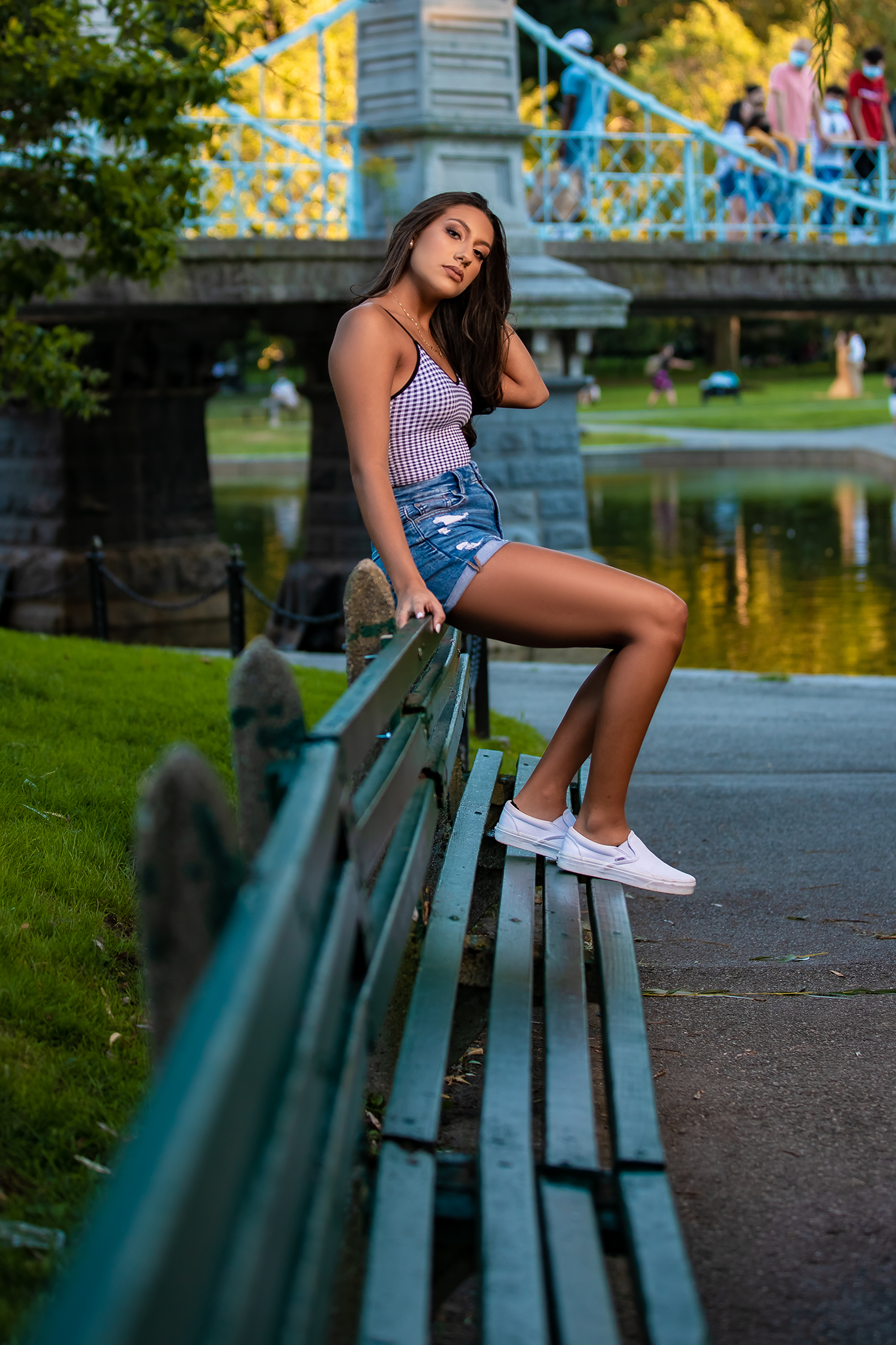 Person poses on green park bench during golden sunset in urban setting.