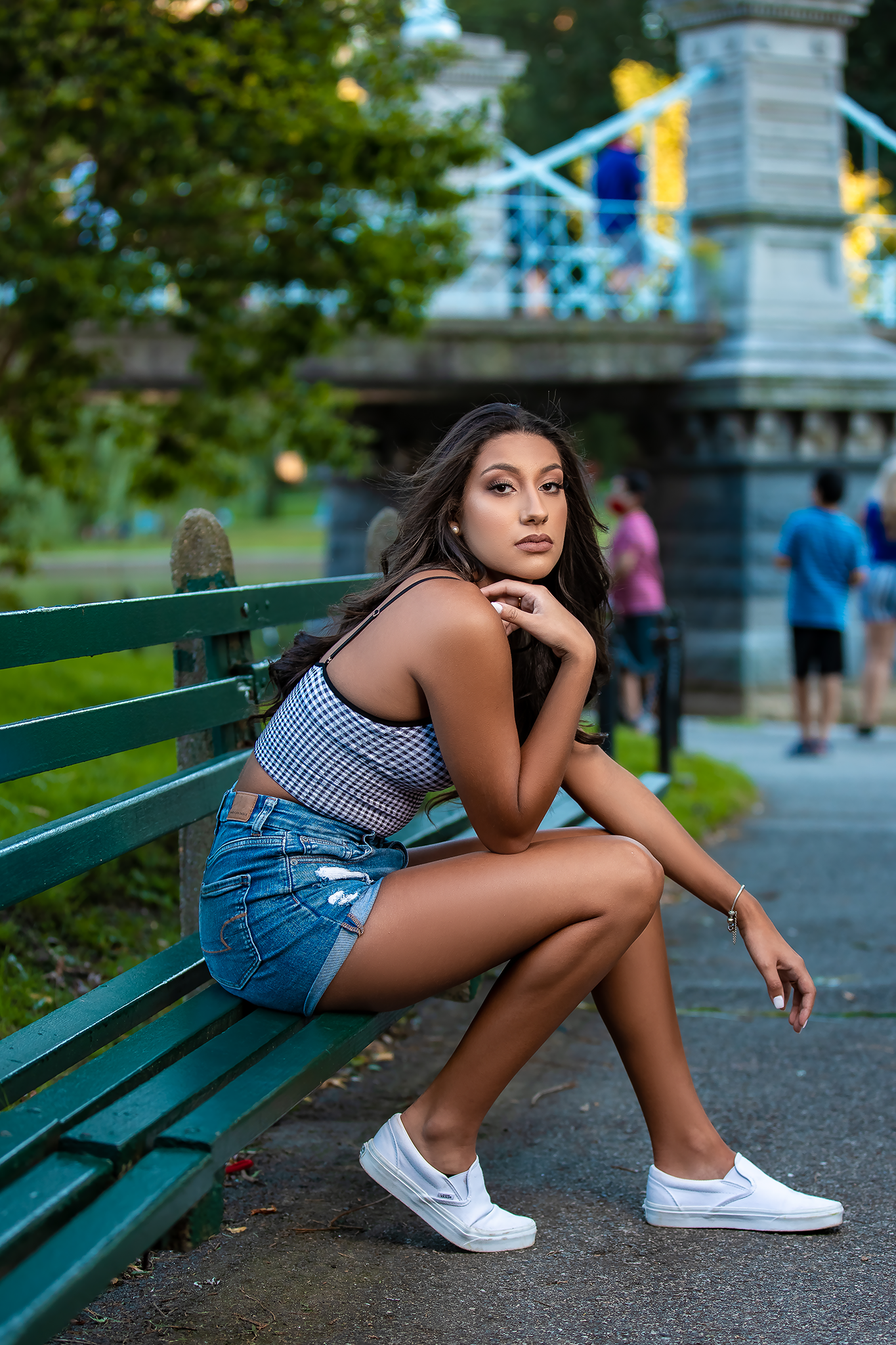 Lifestyle portrait session on green park bench with urban background.