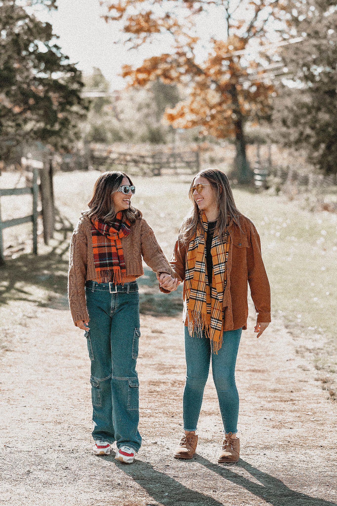 Friends enjoying an autumn walk in matching brown jackets and plaid scarves.