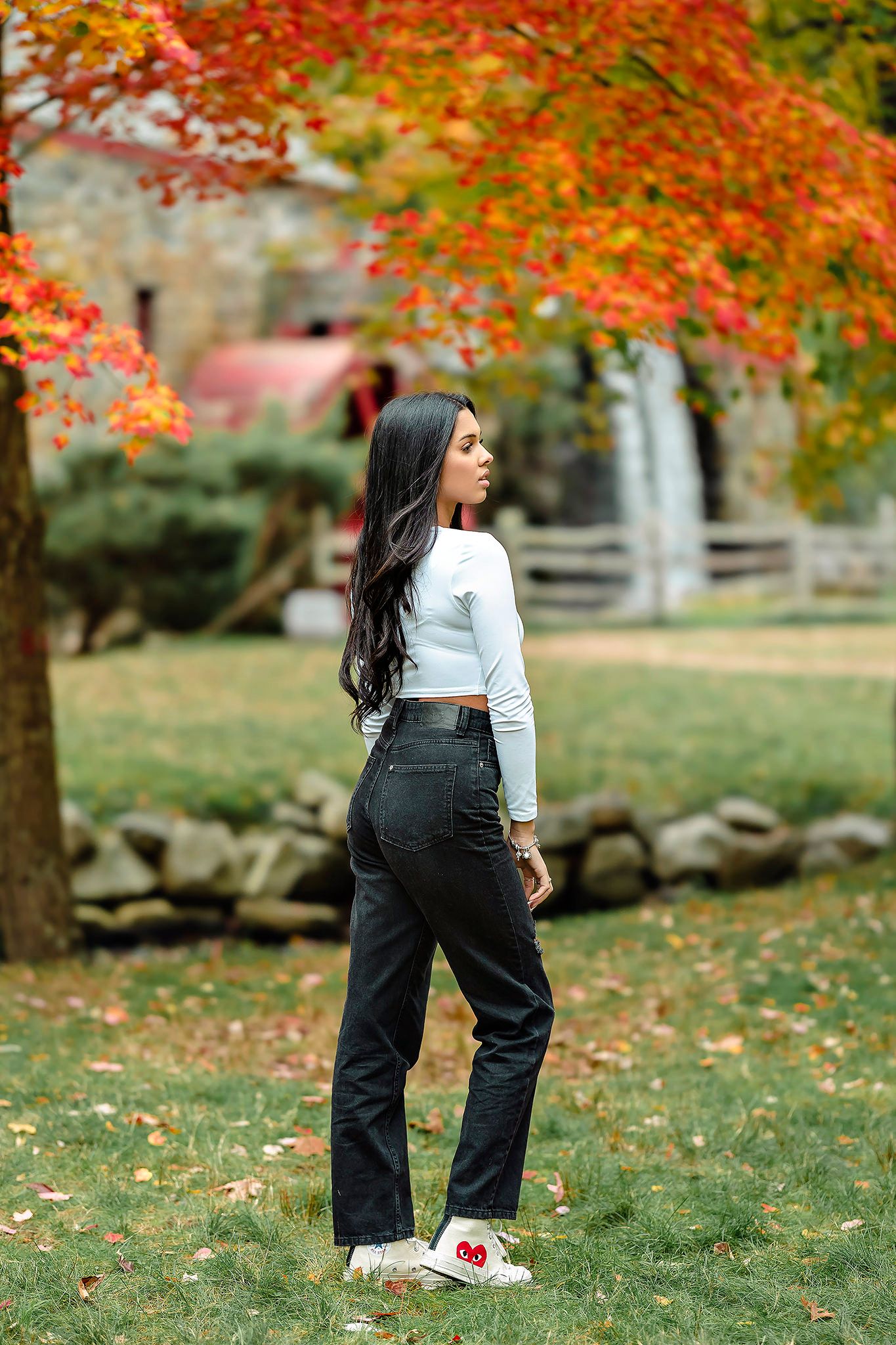 Stylish fall fashion shoot featuring dark denim and crop top against vibrant autumn leaves.