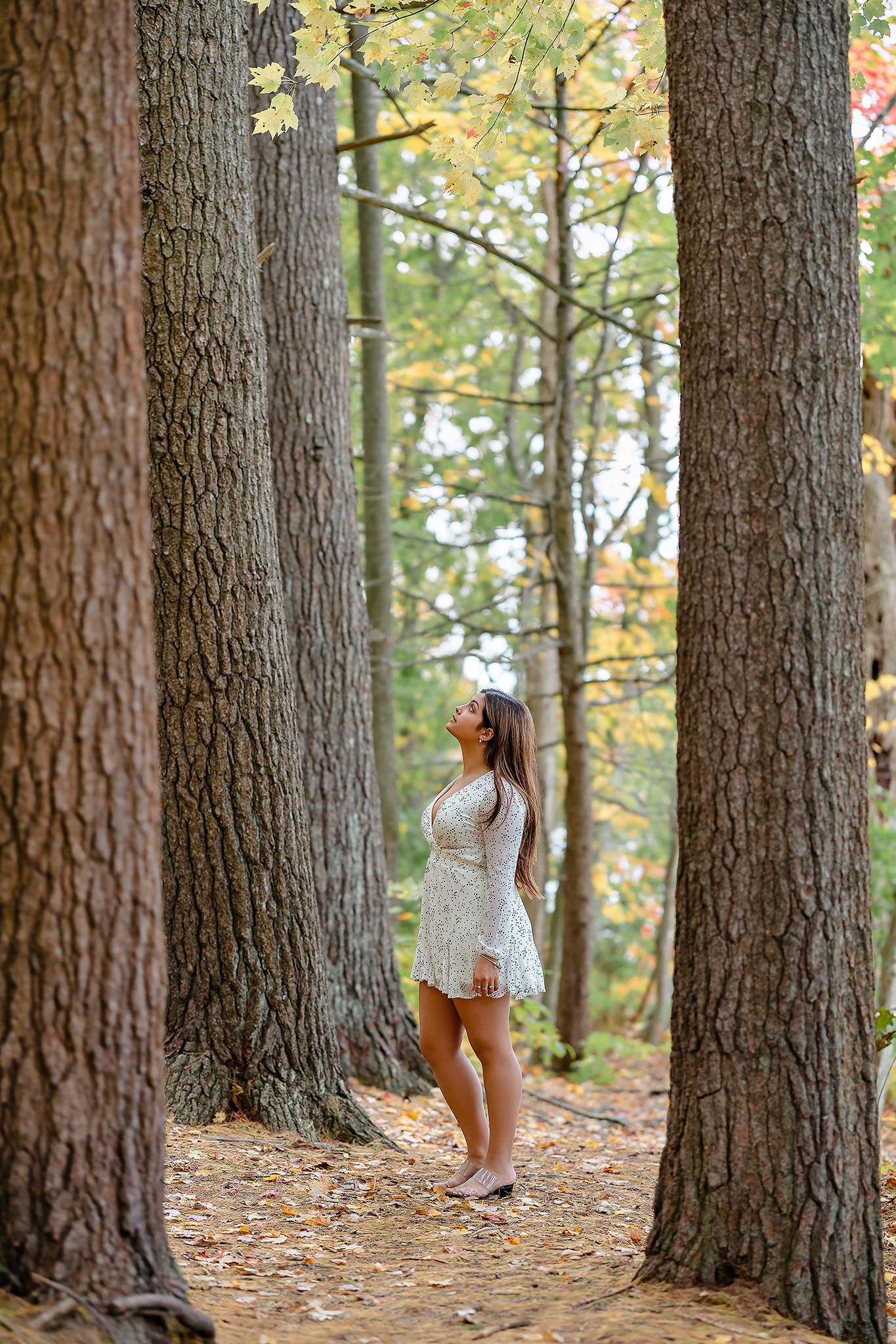 Romantic portrait among tall pine trees on forest path during autumn.