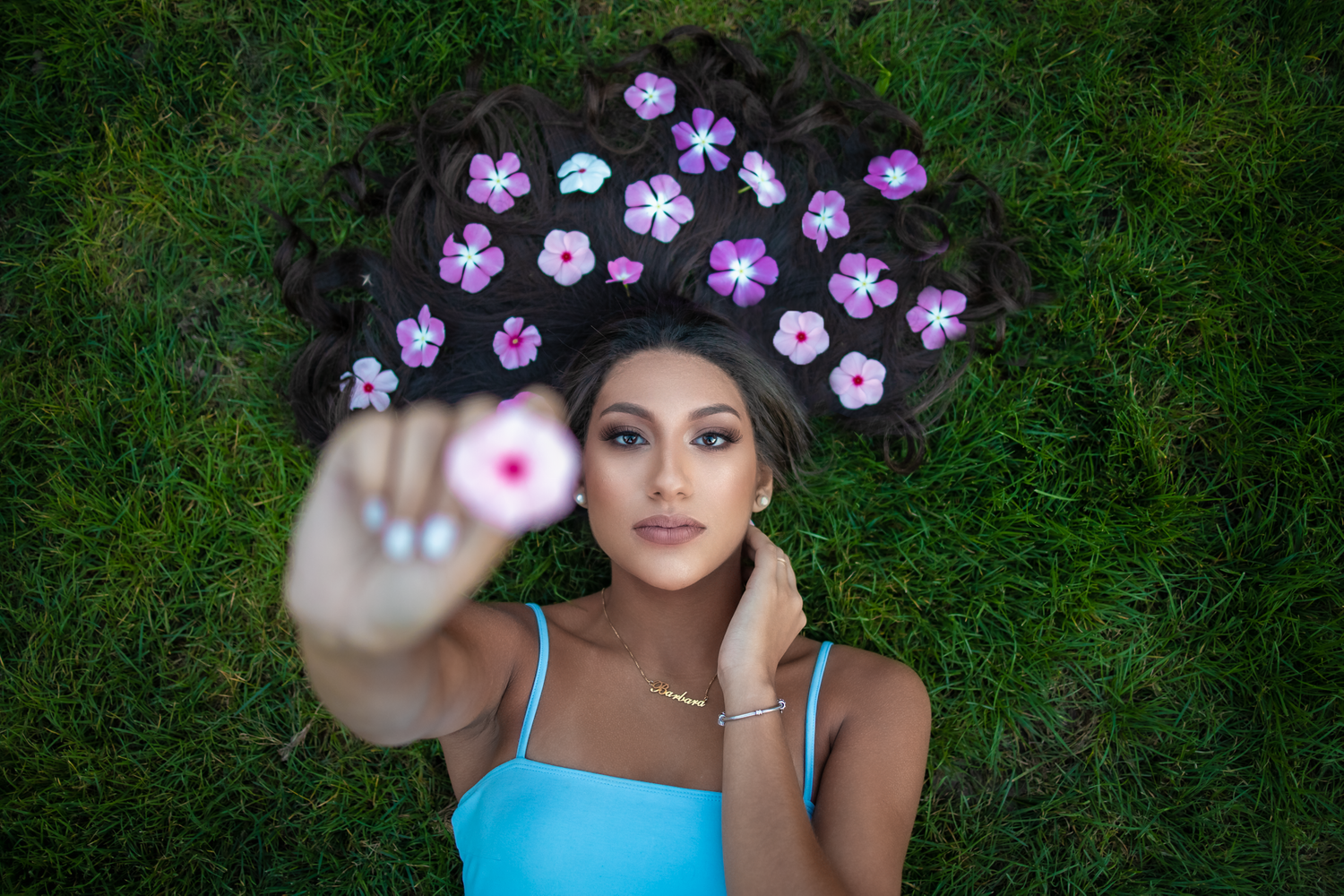 Purple flowers frame a portrait against lush green grass in a creative outdoor photography setting.