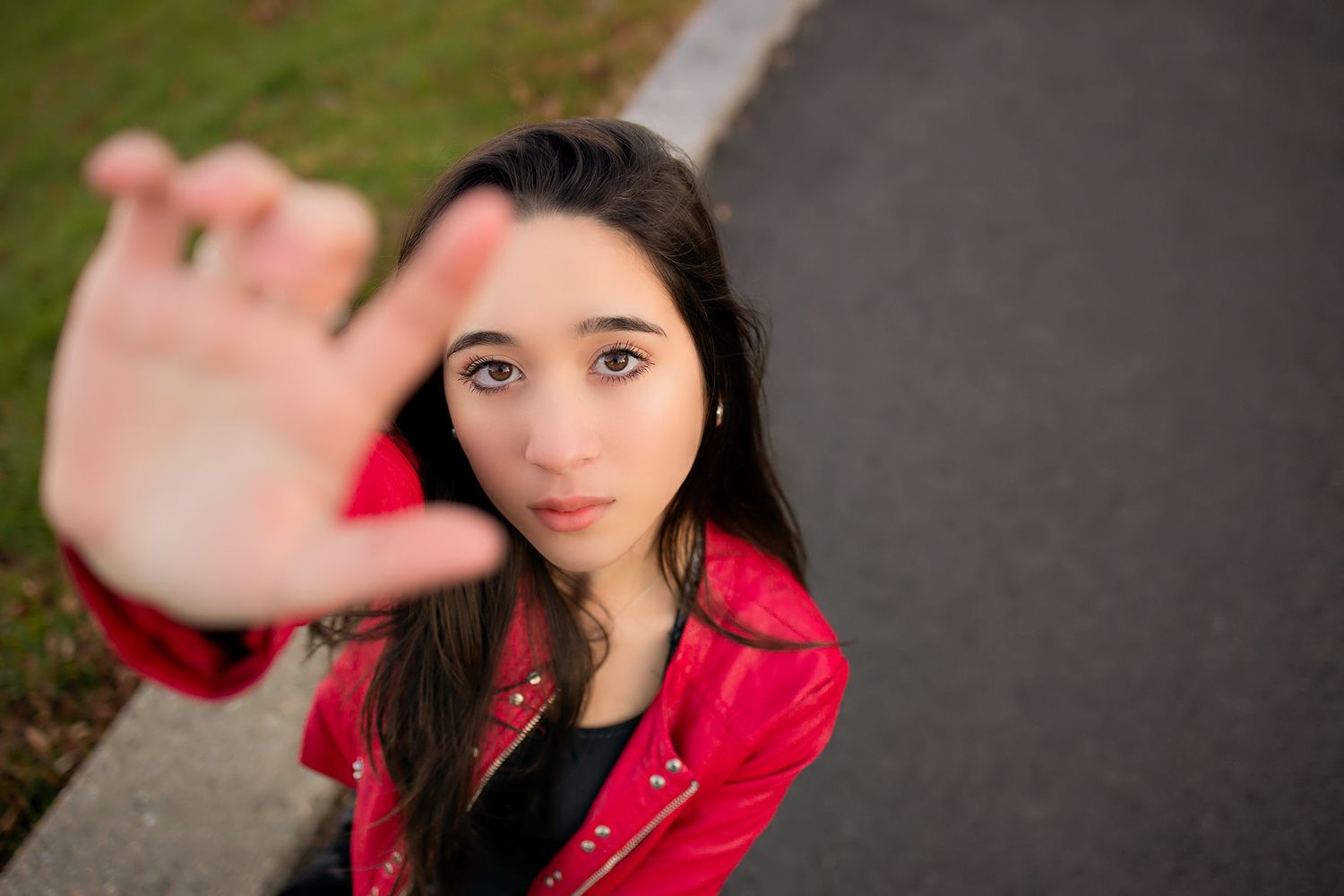 Person in red leather jacket reaches towards camera with blurred background.