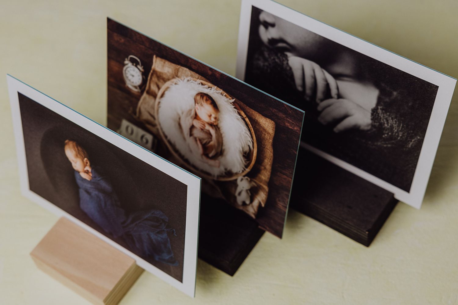 Three photography prints arranged in a standing display on a wooden surface.