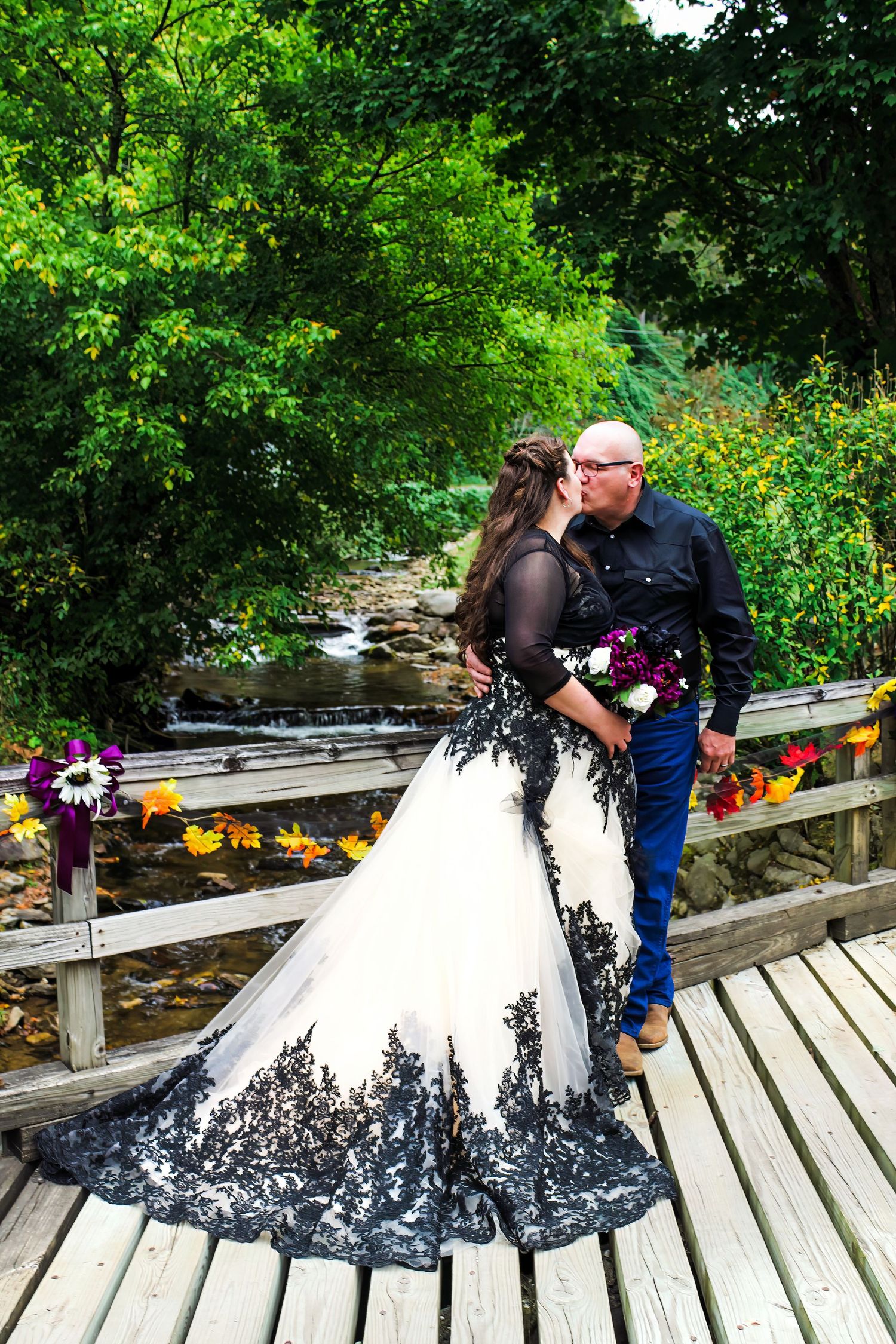 A stunning black and white wedding dress photographed on a wooden bridge over a stream.