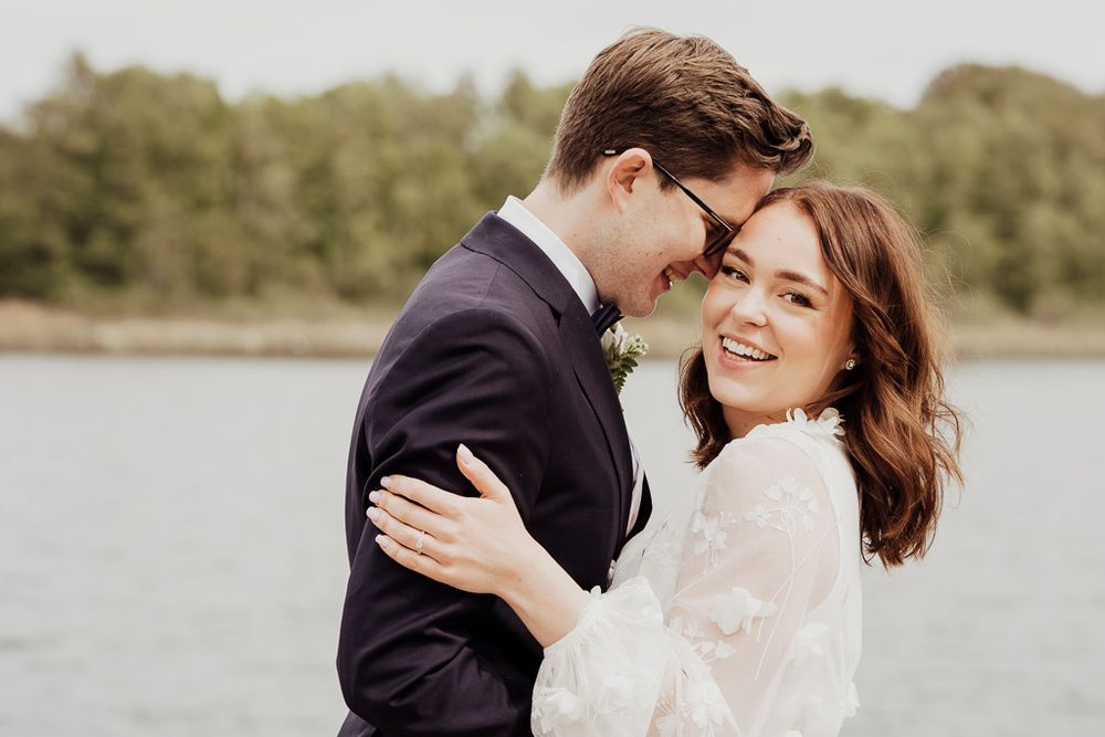 Brudpar håller om varandra glatt. Bröllopsfotograf i Botkyrka utanför Stockholm.
