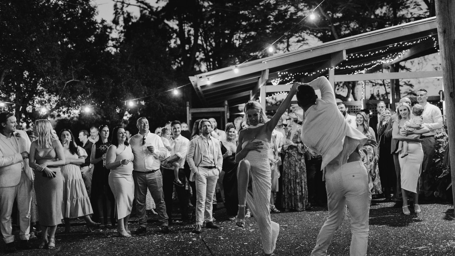 Vintage black and white photo of wedding guests dancing at an outdoor reception.