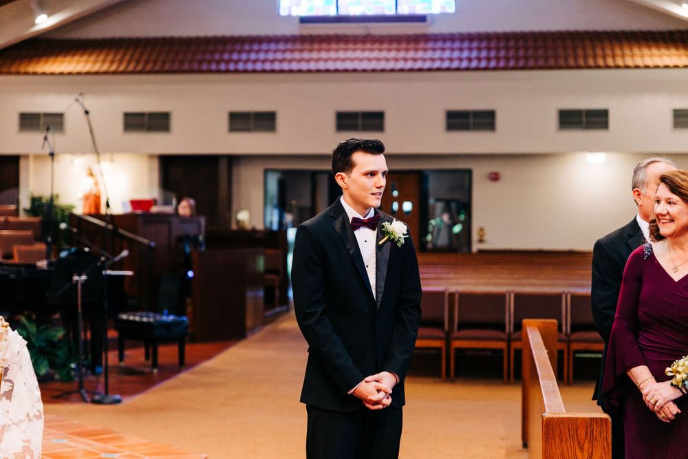 Wedding ceremony in modern church interior with warm lighting and wooden beams.