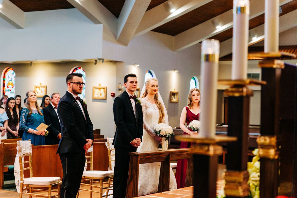 Wedding ceremony in progress inside church with exposed wooden beam architecture.