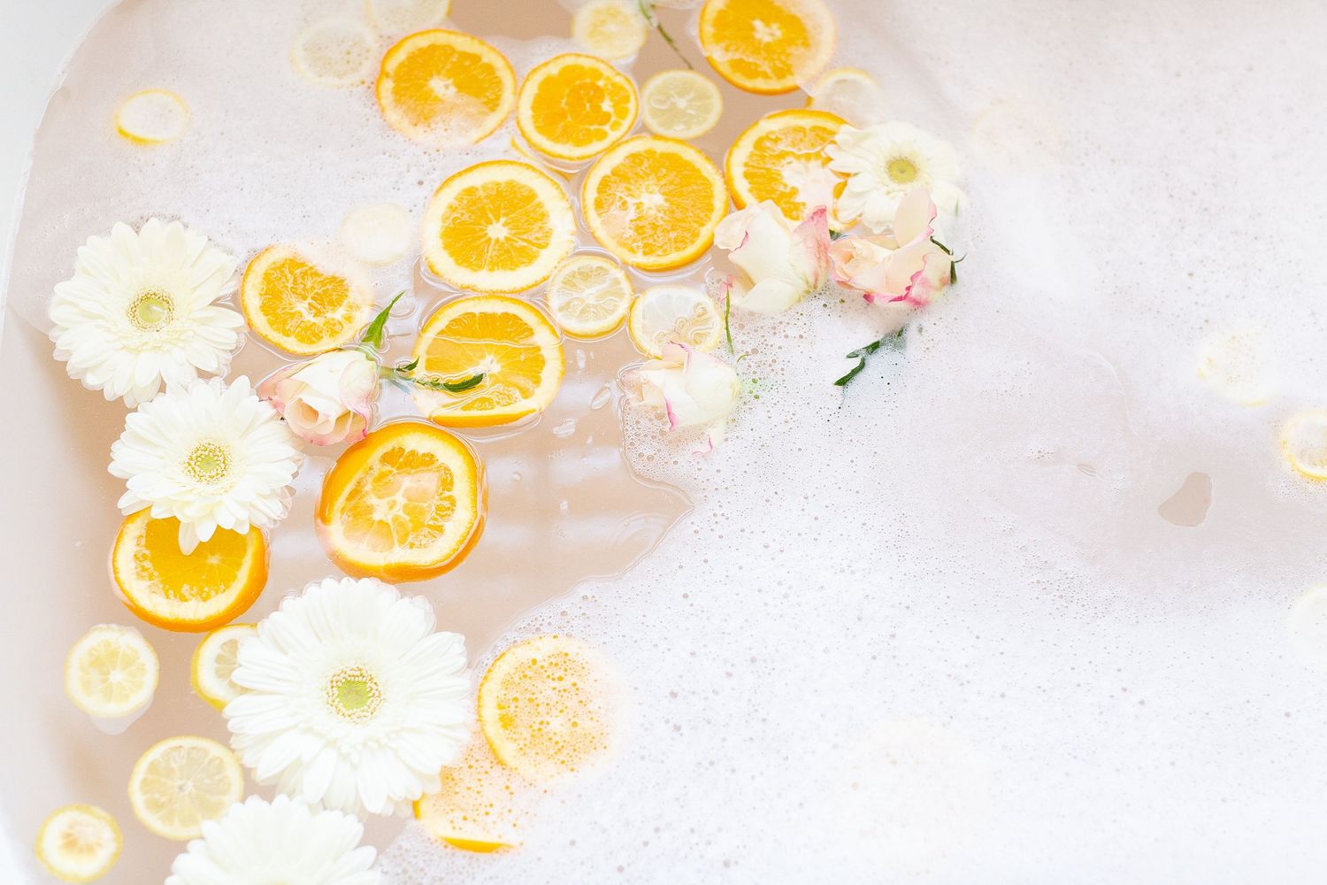 Fresh citrus orange and lemon slices arranged with white flowers on a light background.